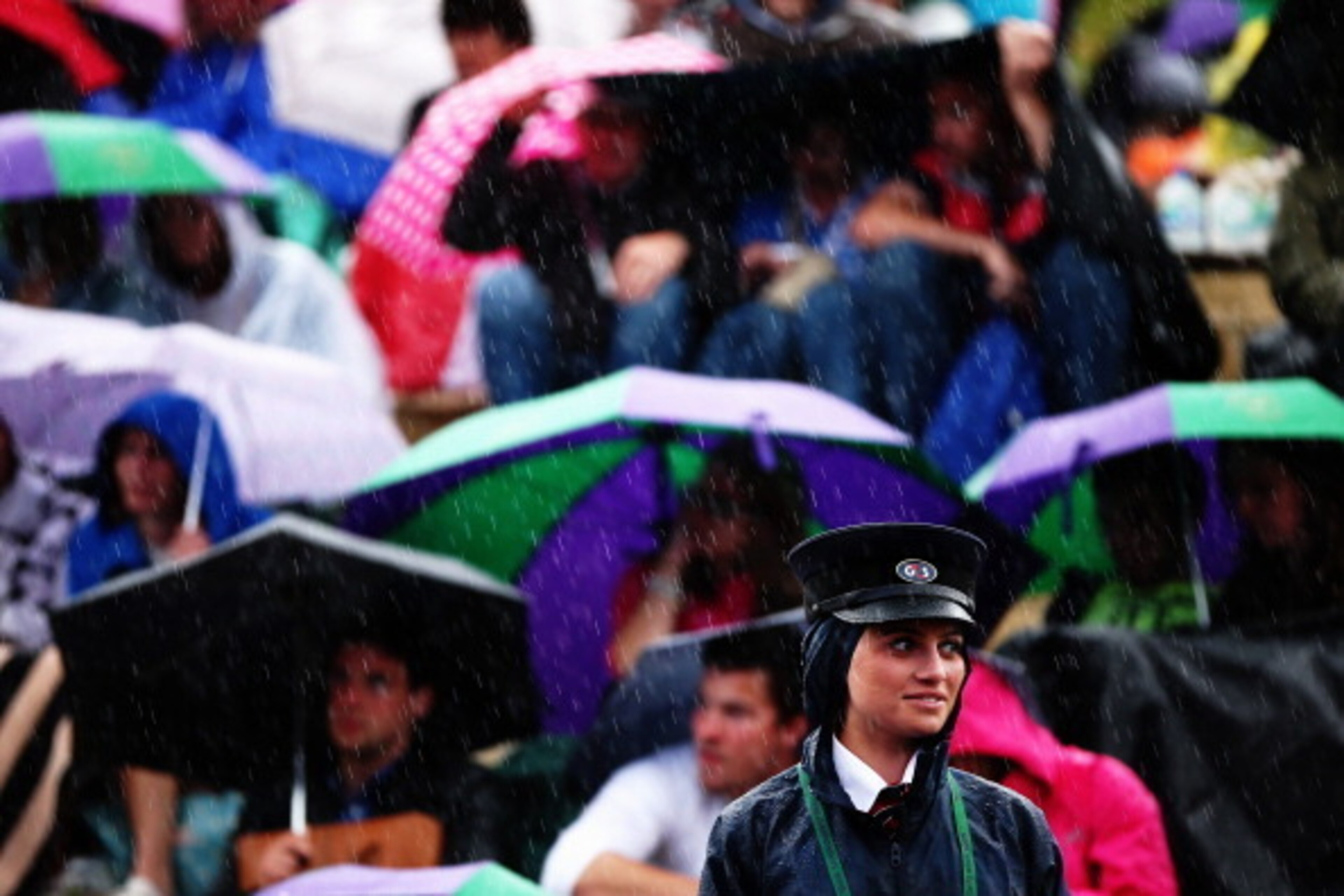 LONDON, ENGLAND - JUNE 30:  G4s Security out in the rain remain in good humor as fans sitting on Murray mound shelter under umbrellas as they watch the Andy Murray against Kevin Anderson game on the big screen on day seven of the Wimbledon Lawn Tennis Cha