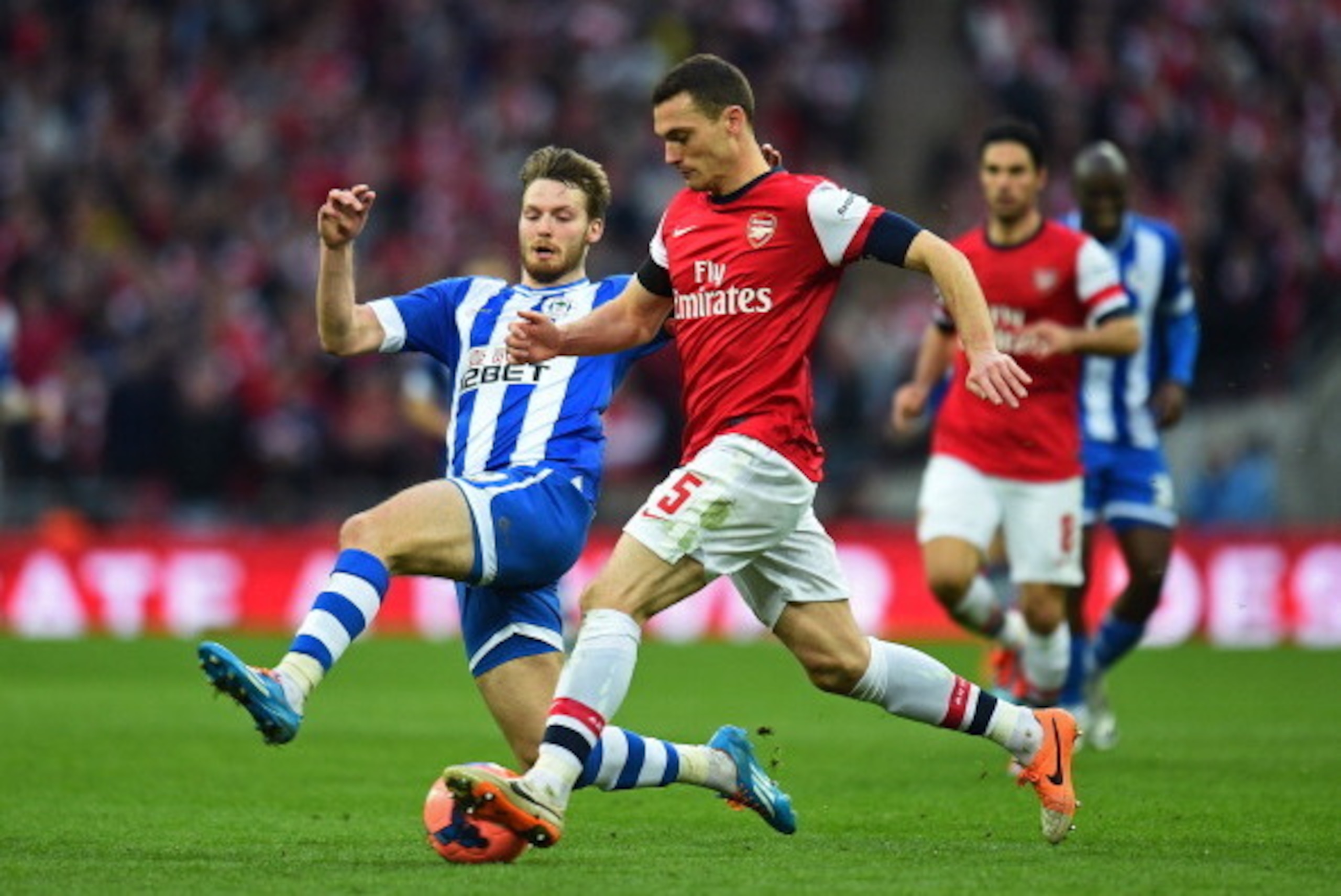 LONDON, ENGLAND - APRIL 12:  Nick Powell of Wigan Athletic challenges Thomas Vermaelen of Arsenal during the FA Cup Semi-Final match between Wigan Athletic and Arsenal at Wembley Stadium on April 12, 2014 in London, England.  (Photo by Shaun Botterill/Get