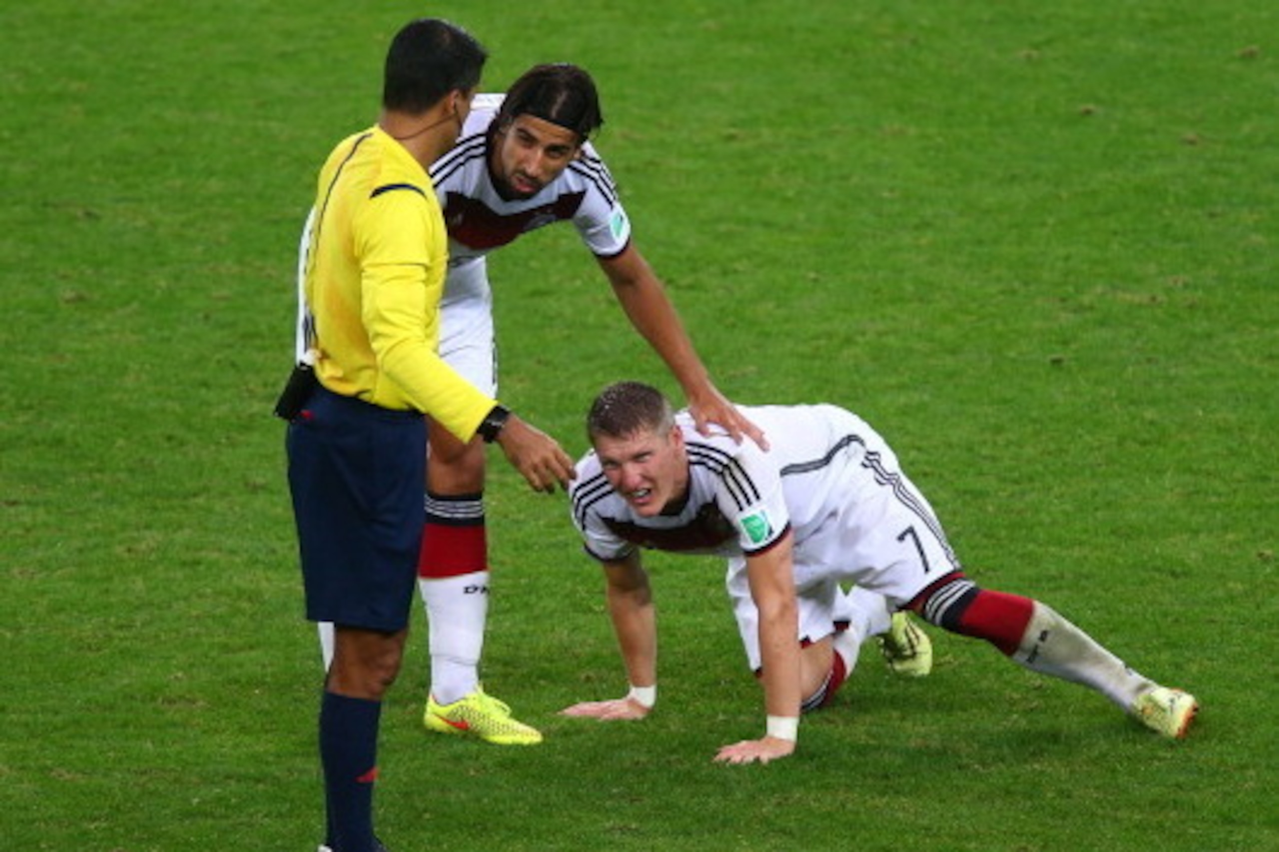 PORTO ALEGRE, BRAZIL - JUNE 30: Bastian Schweinsteiger of Germany kneels on the field as Sami Khedira and referee Sandro Ricci stand over during the 2014 FIFA World Cup Brazil Round of 16 match between Germany and Algeria at Estadio Beira-Rio on June 30, PORTO ALEGRE, BRAZIL - JUNE 30: Bastian Schweinsteiger of Germany kneels on the field as Sami Khedira and referee Sandro Ricci stand over during the 2014 FIFA World Cup Brazil Round of 16 match between Germany and Algeria at Estadio Beira-Rio on June 30,