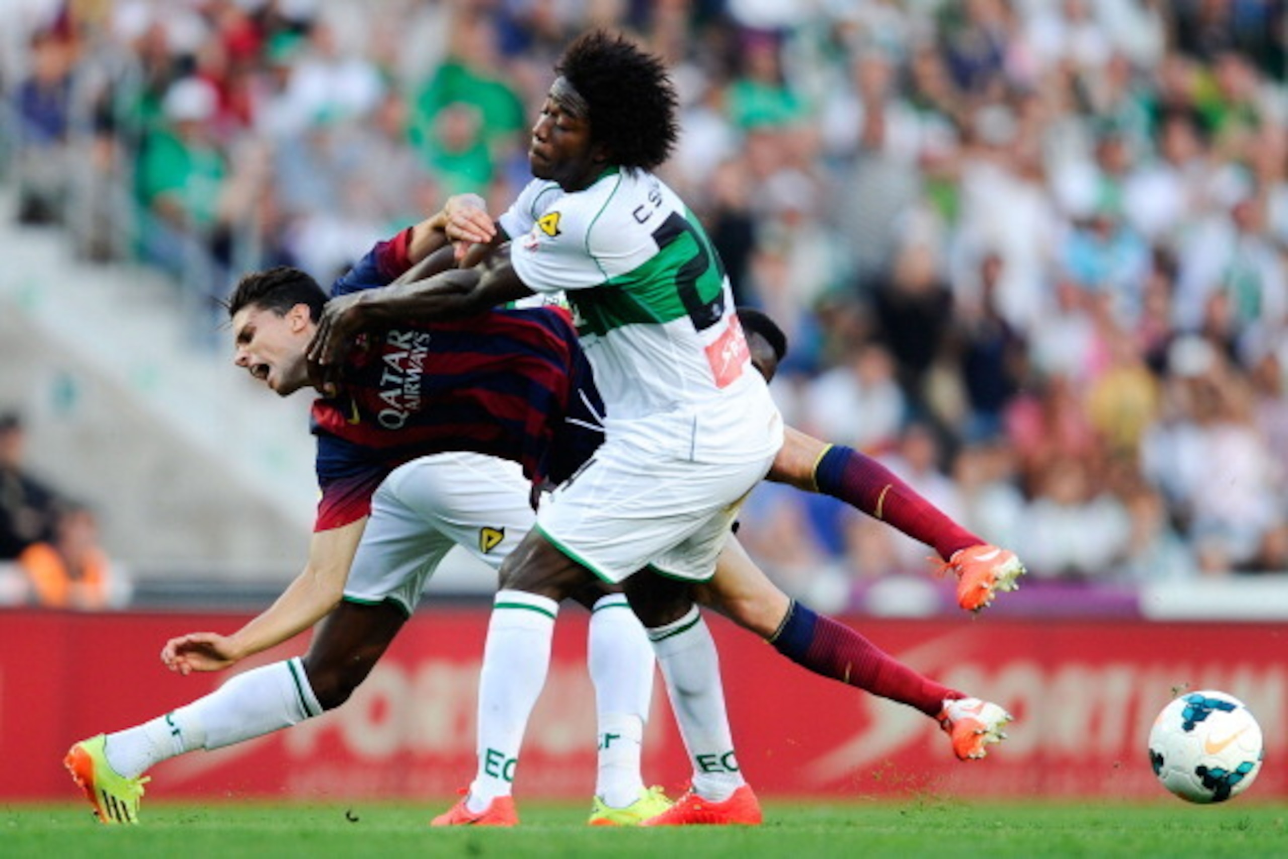 ELCHE, SPAIN - MAY 11:  Marc Bartra of FC Barcelona is brought down by Carlos Sanchez and Richmond Boakye of Elche FC during the La Liga match between Elche FC and FC Barcelona at Estadio Manuel Martinez Valero on May 11, 2014 in Elche, Spain.  (Photo by 
