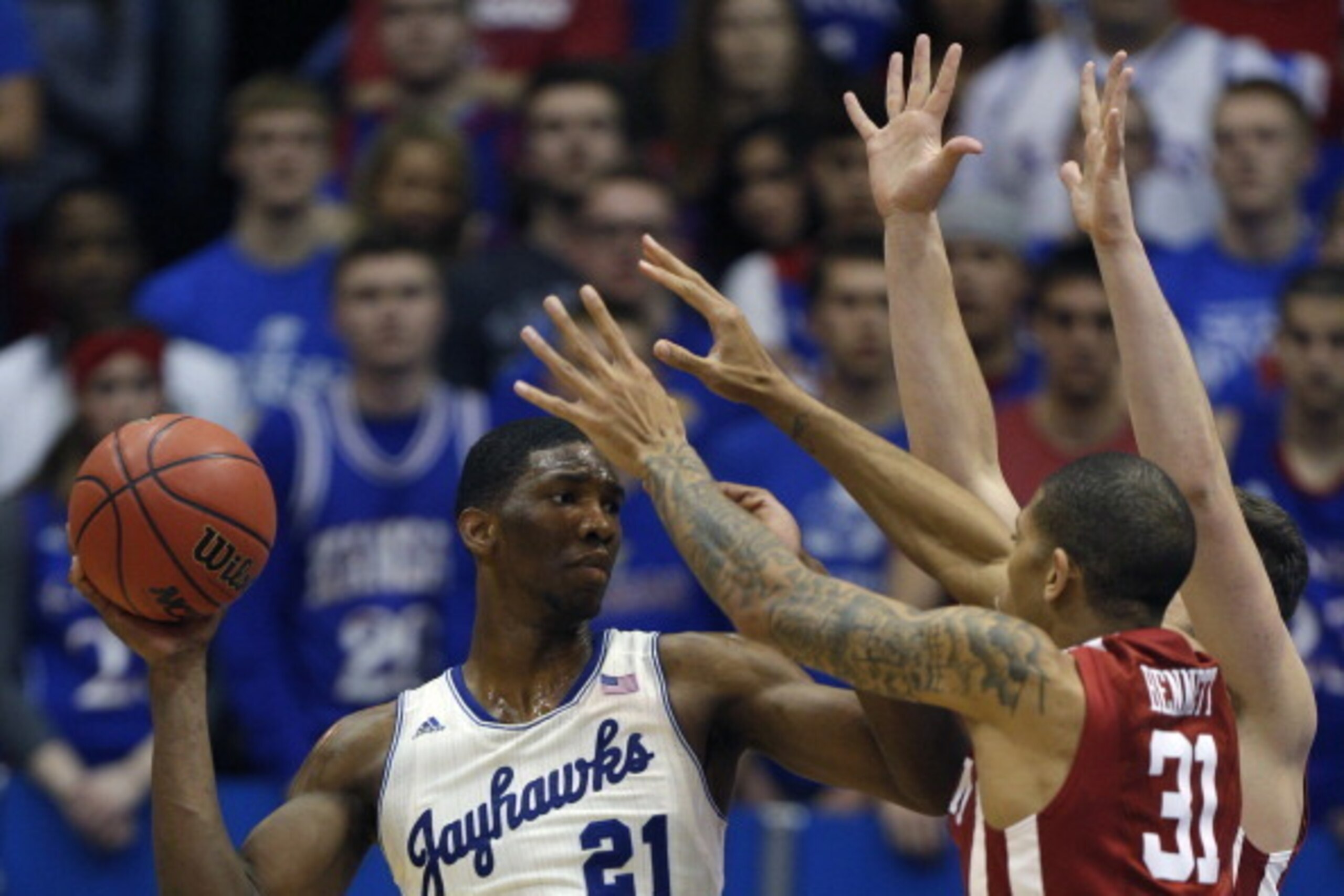 LAWRENCE, KS - FEBRUARY 24:  Joel Embiid #21 of the Kansas Jayhawks looks to pass the ball against D.J. Bennett #31 of the Oklahoma Sooners in the second half at Allen Fieldhouse on February 24, 2014 in Lawrence, Kansas.  Kansas won 83-75. (Photo by Ed Zu