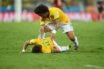 FORTALEZA, BRAZIL - JULY 04:  Neymar of Brazil lies on the field after a challenge as teammate Marcelo reacts during the 2014 FIFA World Cup Brazil Quarter Final match between Brazil and Colombia at Castelao on July 4, 2014 in Fortaleza, Brazil.  (Photo b