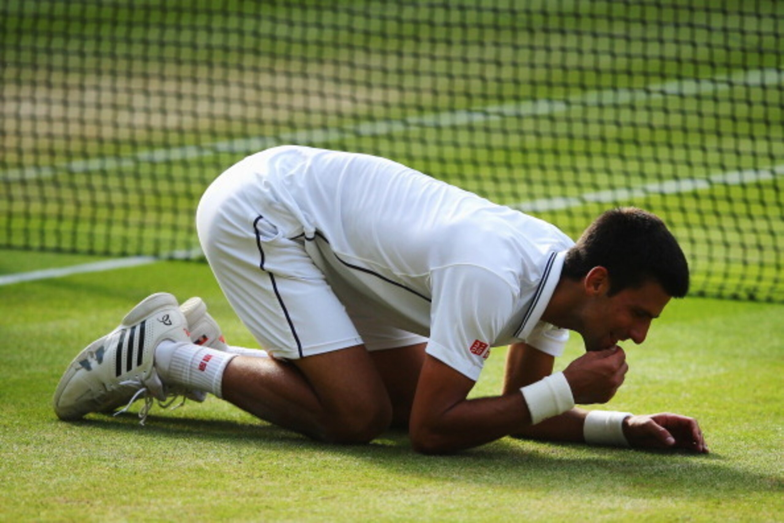 LONDON, ENGLAND - JULY 06:  Novak Djokovic of Serbia eats some of the centre court grass as he kneels on the floor as he celebrates winning the Gentlemen's Singles Final match against Roger Federer of Switzerland on day thirteen of the Wimbledon Lawn Tenn