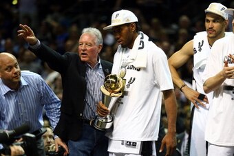SAN ANTONIO, TX - JUNE 15:  Kawhi Leonard #2 of the San Antonio Spurs celebrates with the Bill Russell NBA Finals Most Valuable Player Award and owner Peter Holt after defeating the Miami Heat in Game Five of the 2014 NBA Finals at the AT&T Center on June