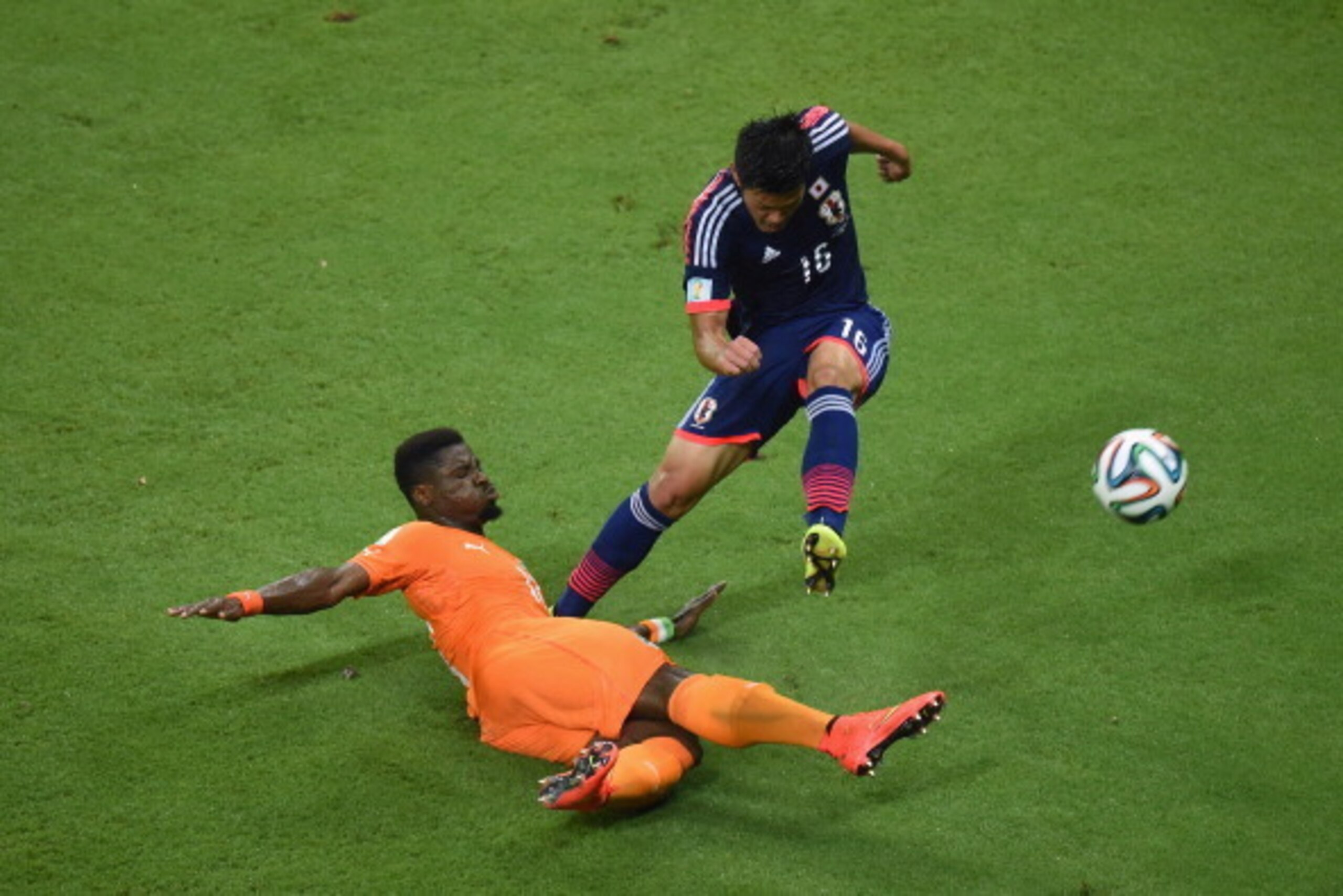 RECIFE, BRAZIL - JUNE 14: Hotaru Yamaguchi of Japan tries to clear the ball past Serge Aurier of the Ivory Coast during the 2014 FIFA World Cup Brazil Group C match  between the Ivory Coast and Japan at Arena Pernambuco on June 14, 2014 in Recife, Brazil.