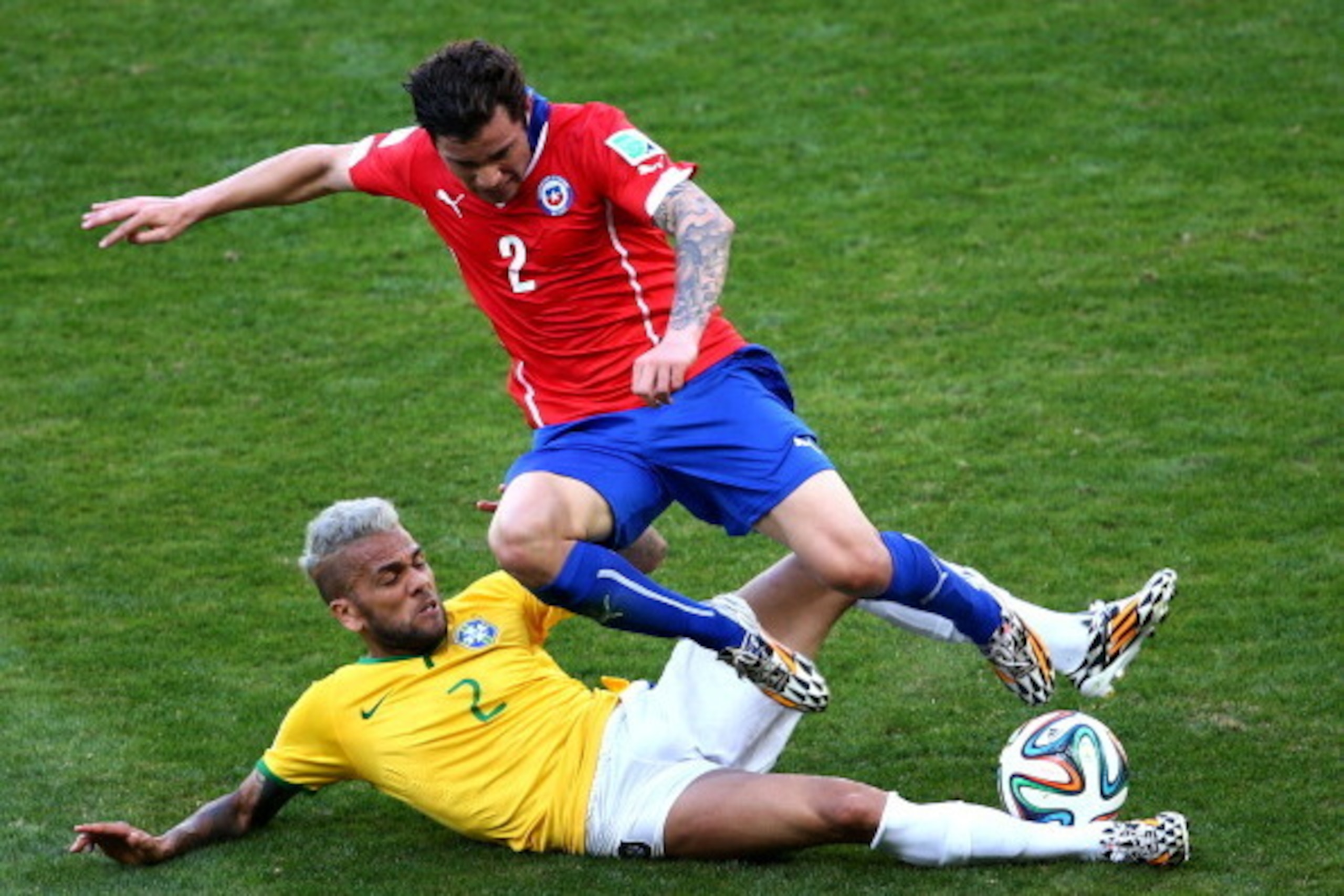 BELO HORIZONTE, BRAZIL - JUNE 28: Dani Alves of Brazil tackles Eugenio Mena of Chile during the 2014 FIFA World Cup Brazil round of 16 match between Brazil and Chile at Estadio Mineirao on June 28, 2014 in Belo Horizonte, Brazil. (Photo by Ian Walton/Get BELO HORIZONTE, BRAZIL - JUNE 28: Dani Alves of Brazil tackles Eugenio Mena of Chile during the 2014 FIFA World Cup Brazil round of 16 match between Brazil and Chile at Estadio Mineirao on June 28, 2014 in Belo Horizonte, Brazil. (Photo by Ian Walton/Get