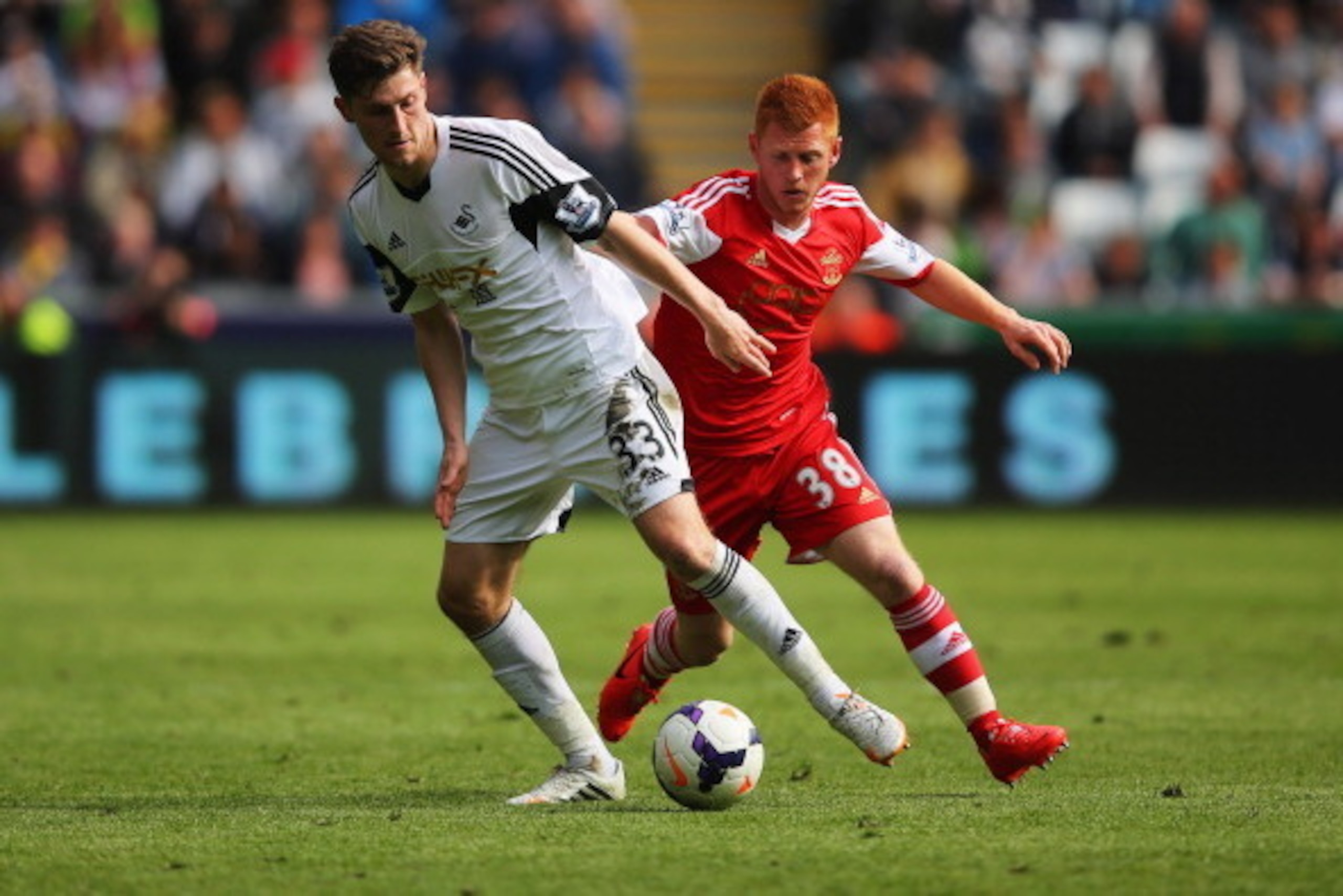 SWANSEA, WALES - MAY 03:  Ben Davies of Swansea City is watched by Harrison Reed of Southampton during the Barclays Premier League match between Swansea City and Southampton at Liberty Stadium on May 3, 2014 in Swansea, Wales.  (Photo by Clive Rose/Getty 