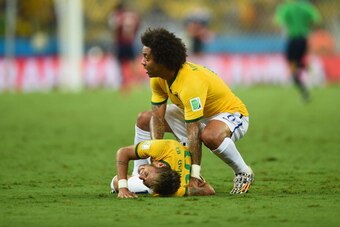 FORTALEZA, BRAZIL - JULY 04:  Neymar of Brazil lies on the field after a challenge as teammate Marcelo reacts during the 2014 FIFA World Cup Brazil Quarter Final match between Brazil and Colombia at Castelao on July 4, 2014 in Fortaleza, Brazil.  (Photo b