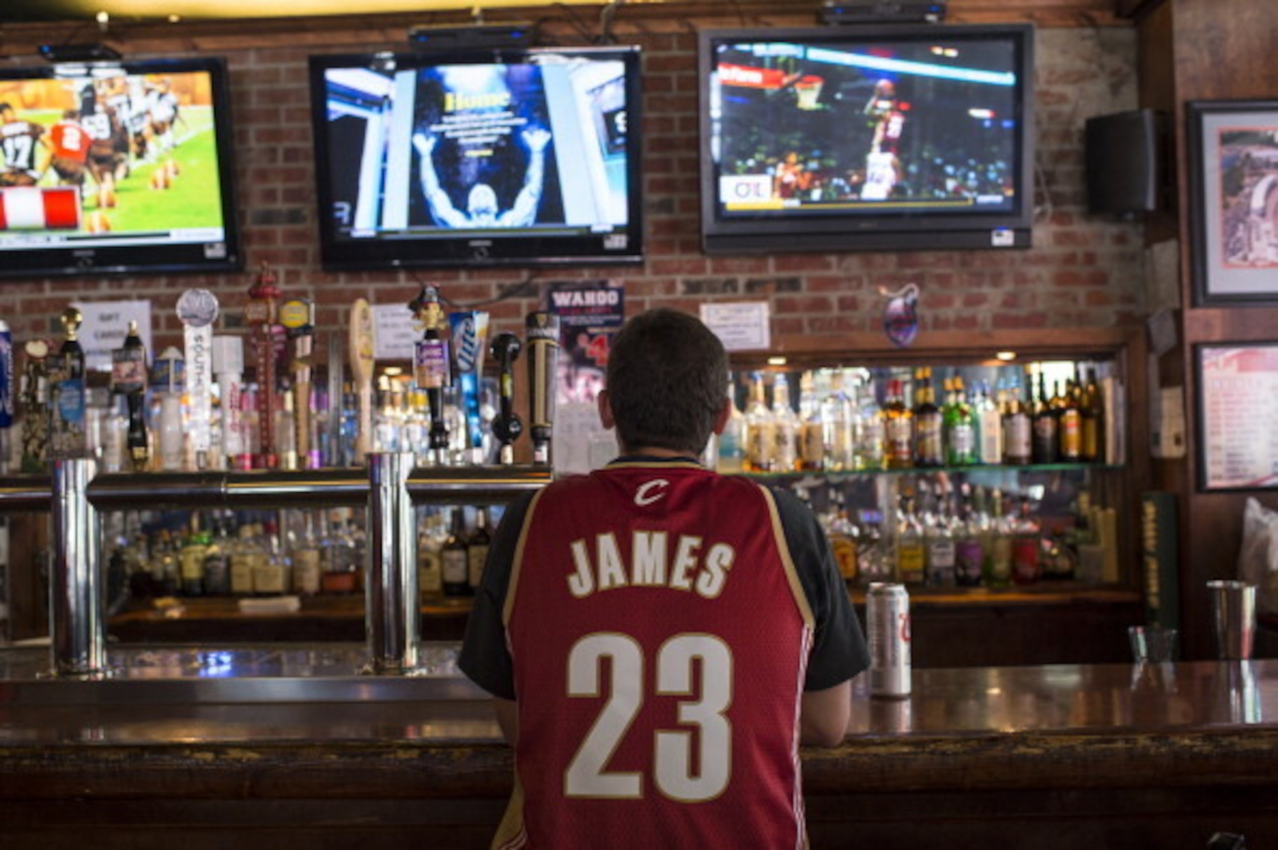 CLEVELAND, OH - JULY 11: A Cleveland Cavaliers fan wearing a Lebron James jersey watches news coverage of LeBron James return to Cleveland at Panini's Bar and Grille in downtown Cleveland on July 11, 2014 in Cleveland, Ohio (Photo by Angelo Merendino/Gett