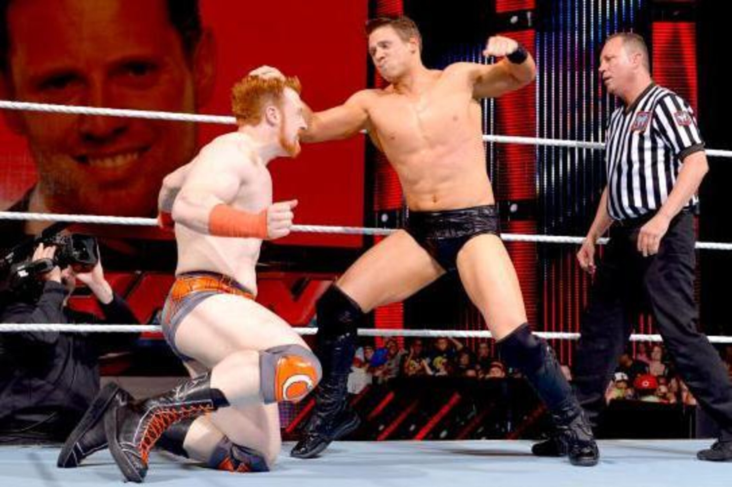The Miz attacks Sheamus. Note his face on the big screen behind them.