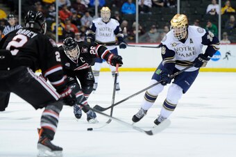 ST PAUL, MN - MARCH 29: Nic Dowd #26 of the St. Cloud State Huskies strips the puck from Stephen Johns #28 of the Notre Dame Fighting Irish as Jarrod Rabey #2 of the St. Cloud State Huskies looks on during the second period of the West Regional game of th
