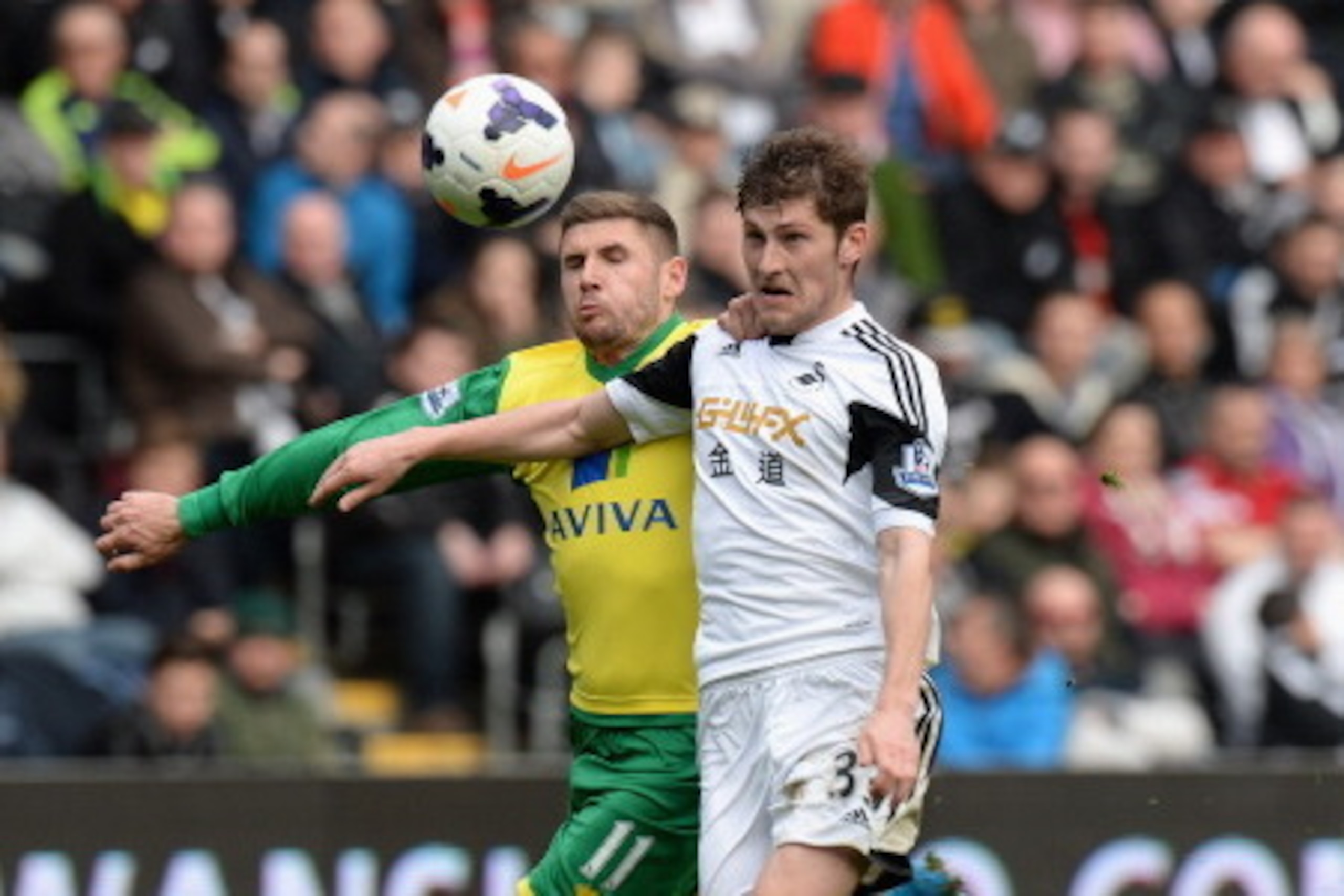 SWANSEA, WALES - MARCH 29:  Ben Davies of Swansea City tackled by Gary Hooper of Norwich City during the Barclays Premier League match between Swansea City and Norwich City at Liberty Stadium on March 29, 2014 in Swansea, Wales.  (Photo by Tony Marshall/G
