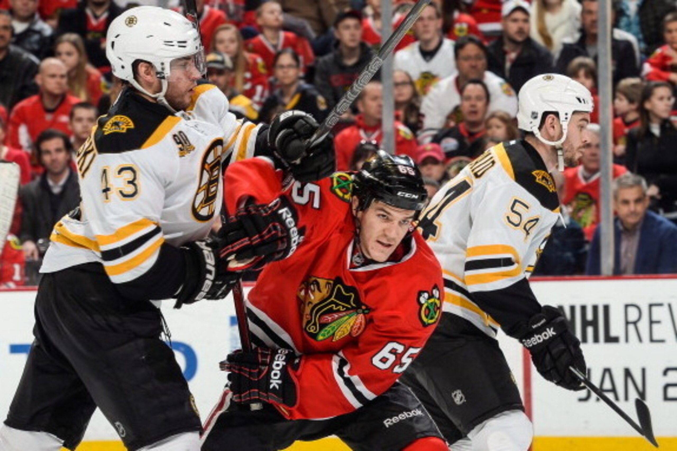 CHICAGO, IL - JANUARY 19: Matt Bartkowski #43 of the Boston Bruins and Andrew Shaw #65 of the Chicago Blackhawks get physical next to Adam McQuaid #54 of the Bruins during the NHL game on January 19, 2014 at the United Center in Chicago, Illinois. (Photo 