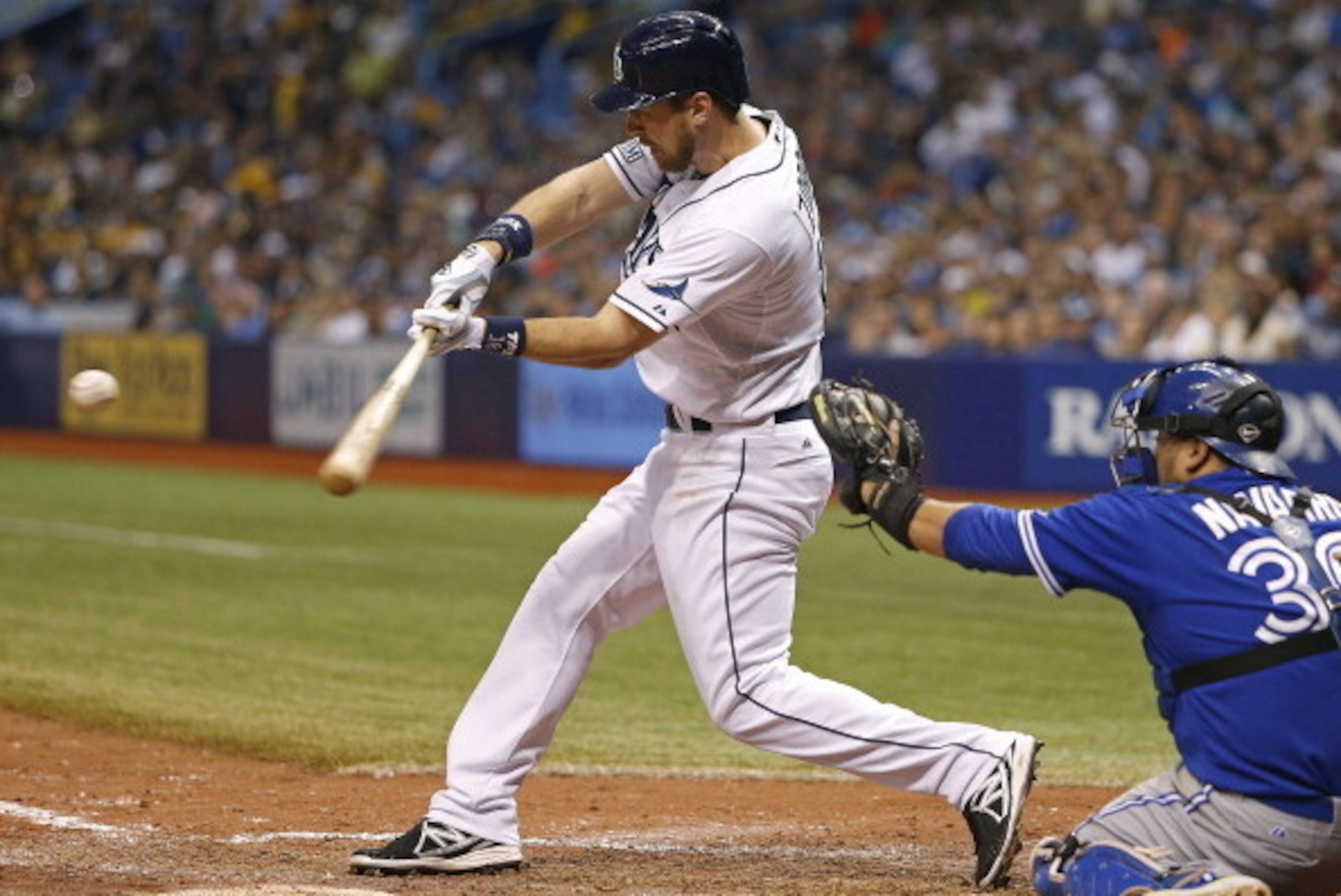 ST. PETERSBURG, FL - JULY 12:  Ben Zobrist #18 of the Tampa Bay Rays hits a sacrifice fly to center field in front of catcher Dioner Navarro #30 of the Toronto Blue Jays to score teammate Yunel Escobar during the seventh inning of a game on July 12, 2014 