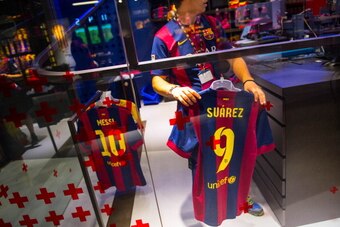 BARCELONA, SPAIN - JULY 12:  An employee hangs a Luis Suarez shirt after printing his name and number on it at the FC Barcelona official store on July 12, 2014 in Barcelona, Spain.  (Photo by David Ramos/Getty Images)