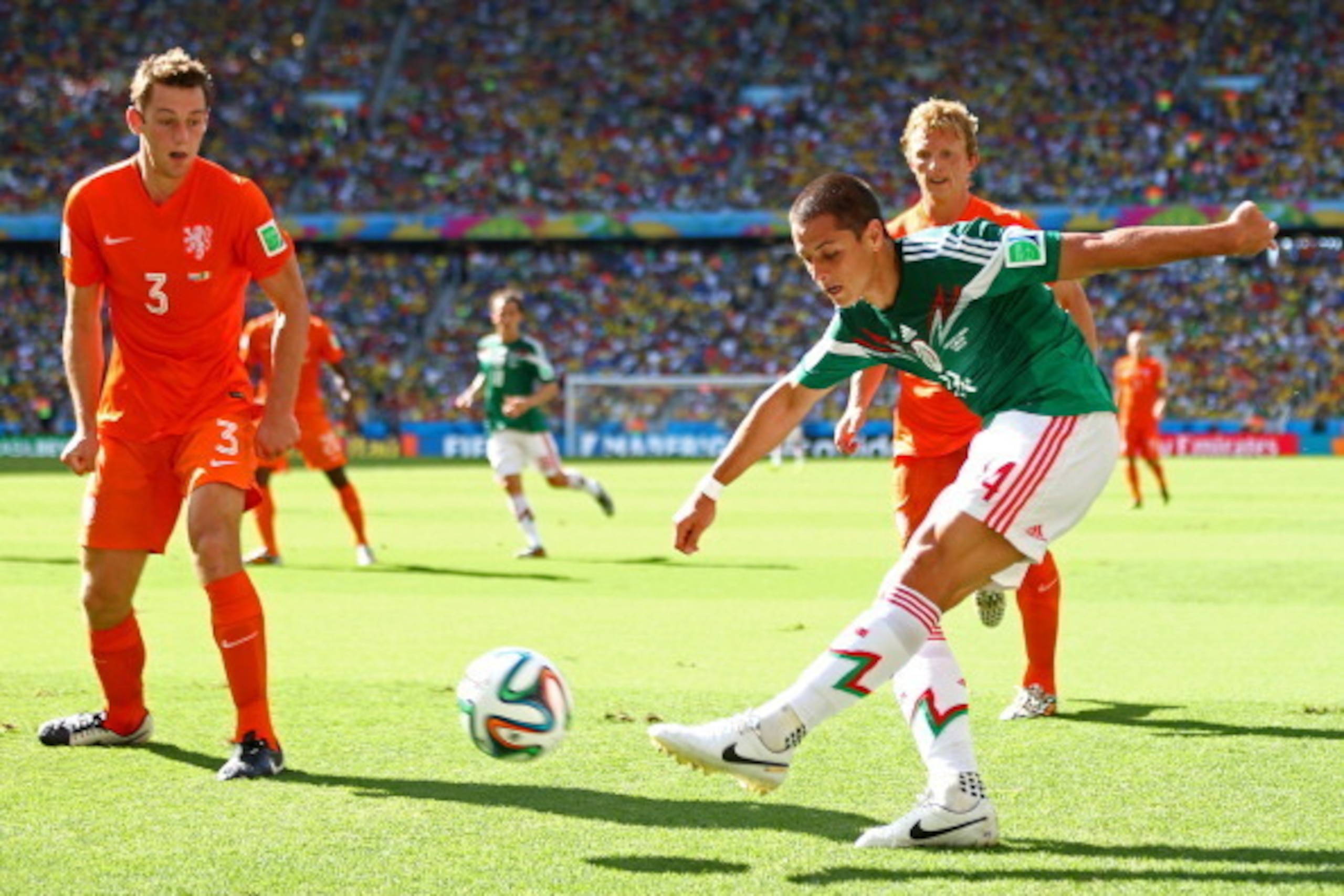 FORTALEZA, BRAZIL - JUNE 29: Javier Hernandez of Mexico strikes the ball against Stefan de Vrij of the Netherlands during the 2014 FIFA World Cup Brazil Round of 16 match between Netherlands and Mexico at Castelao on June 29, 2014 in Fortaleza, Brazil.  (