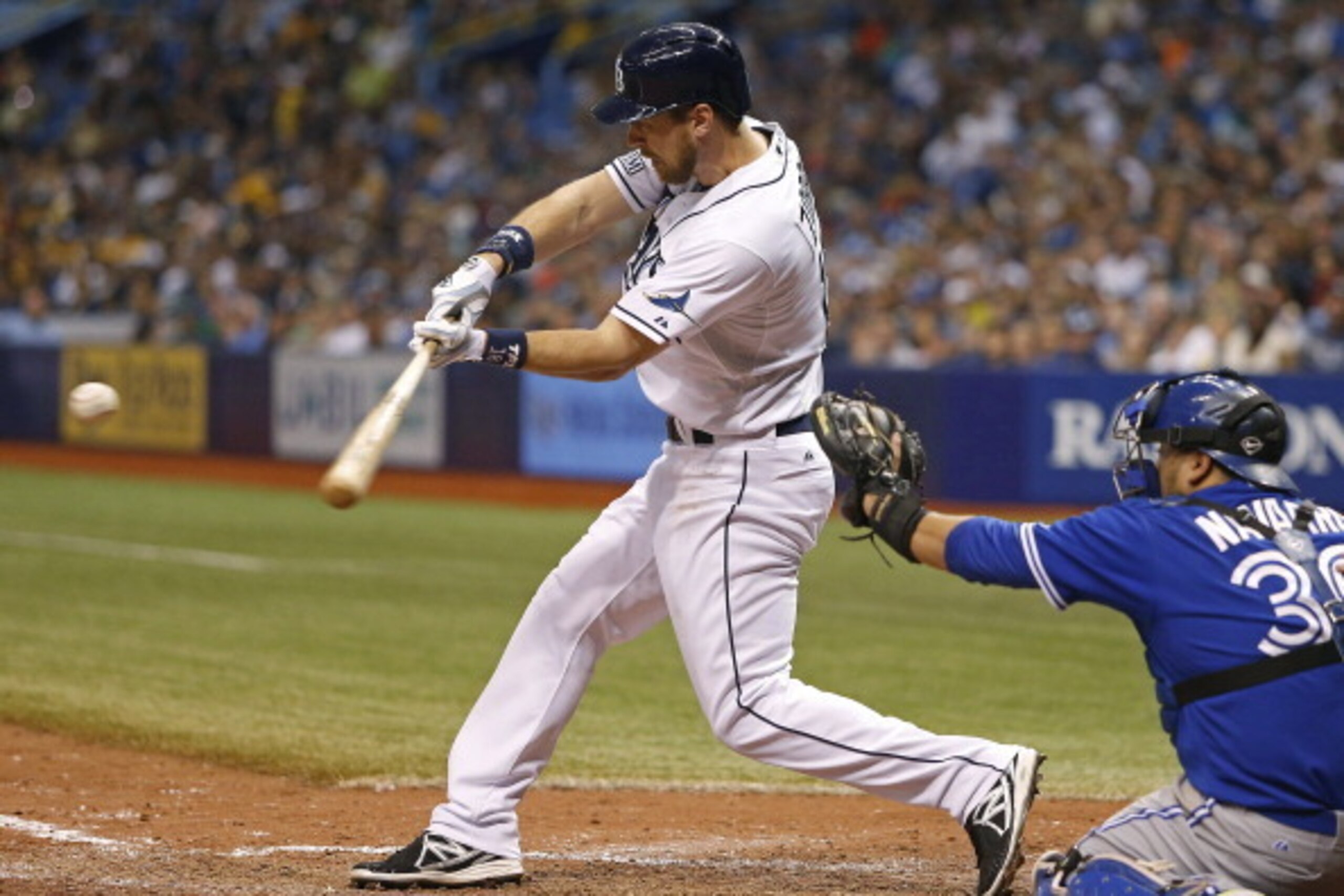ST. PETERSBURG, FL - JULY 12:  Ben Zobrist #18 of the Tampa Bay Rays hits a sacrifice fly to center field in front of catcher Dioner Navarro #30 of the Toronto Blue Jays to score teammate Yunel Escobar during the seventh inning of a game on July 12, 2014 