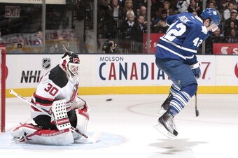 TORONTO, CANADA - DECEMBER 6:  Tyler Bozak #42 of the Toronto Maple Leafs jumps through the crease as goalie Martin Brodeur #30 of the New Jersey Devils makes a glove save during NHL game action December 6, 2011 at Air Canada Centre in Toronto, Ontario, C