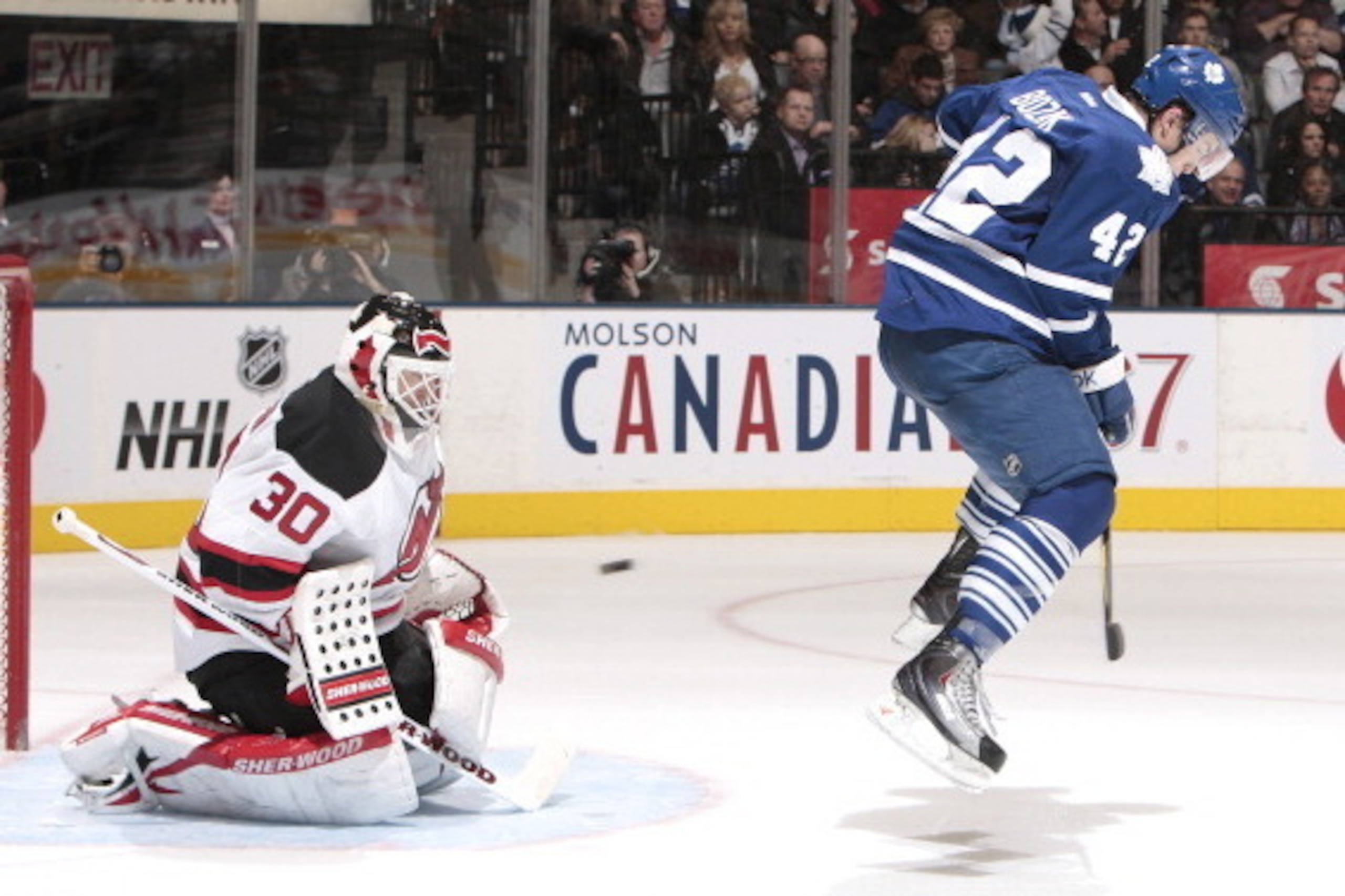 TORONTO, CANADA - DECEMBER 6:  Tyler Bozak #42 of the Toronto Maple Leafs jumps through the crease as goalie Martin Brodeur #30 of the New Jersey Devils makes a glove save during NHL game action December 6, 2011 at Air Canada Centre in Toronto, Ontario, C