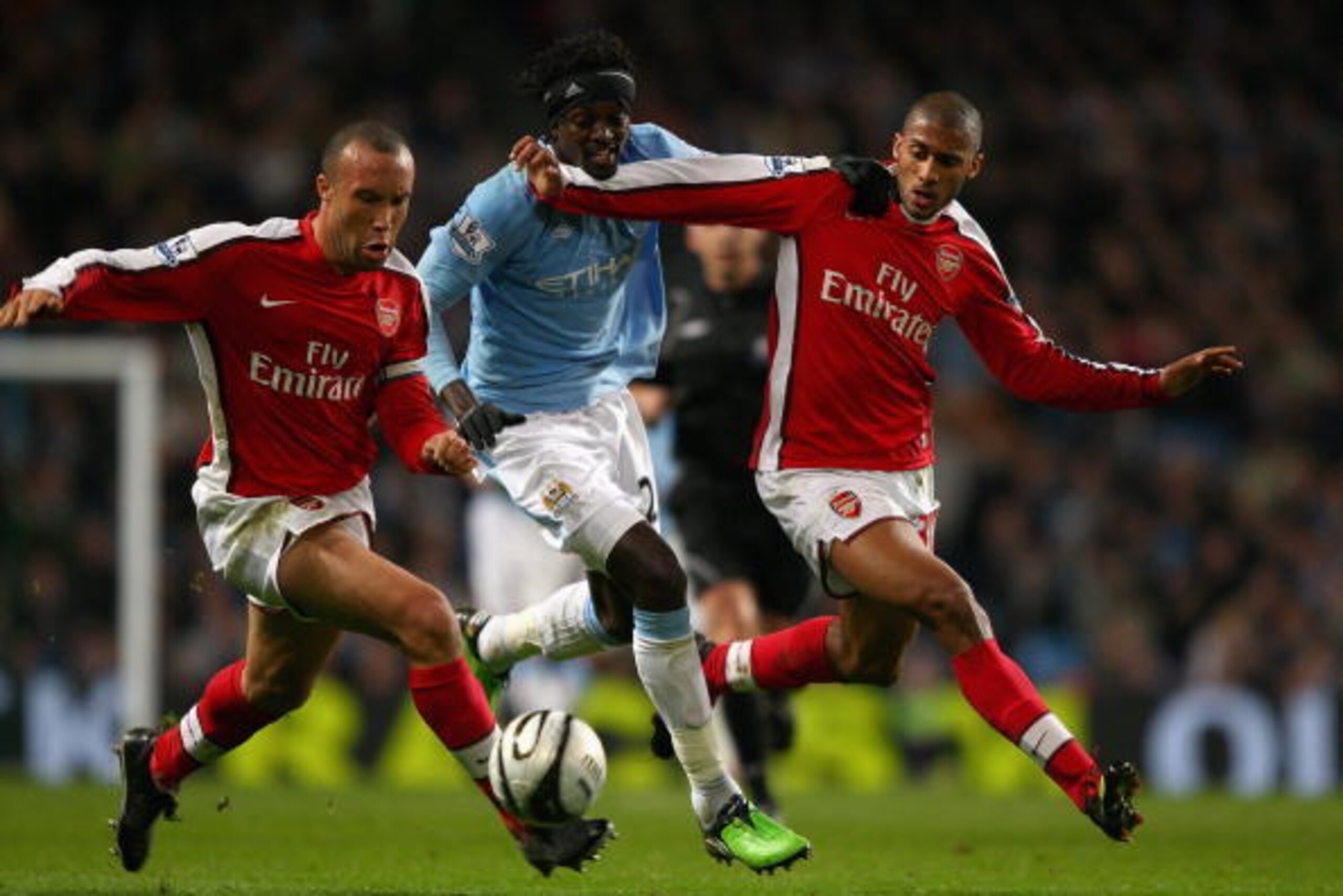 MANCHESTER, ENGLAND - DECEMBER 02:  Emmanuel Adebayor of Manchester City holds off Mikael Silvestre and Armand Traore of Arsenal during the Carling Cup quarter final match between Manchester City and Arsenal at the City of Manchester Stadium on December 2