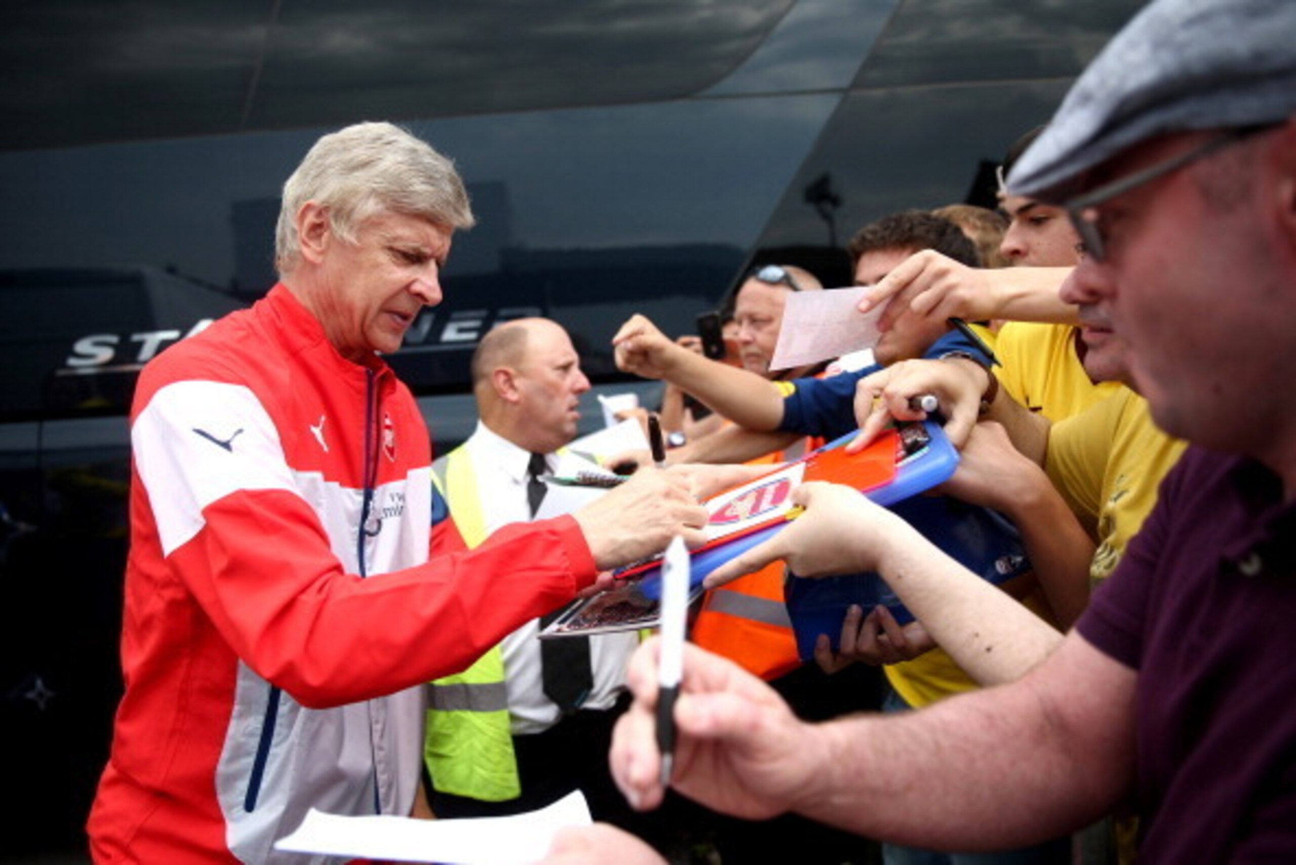 BOREHAMWOOD, ENGLAND - JULY 19:  Arsenal manager Arsene Wenger signs autographs for fans as he arrives ahead of the pre season friendly match between Borehamwood and Arsenal at Meadow Park on July 19, 2014 in Borehamwood, England.  (Photo by Jordan Mansfi