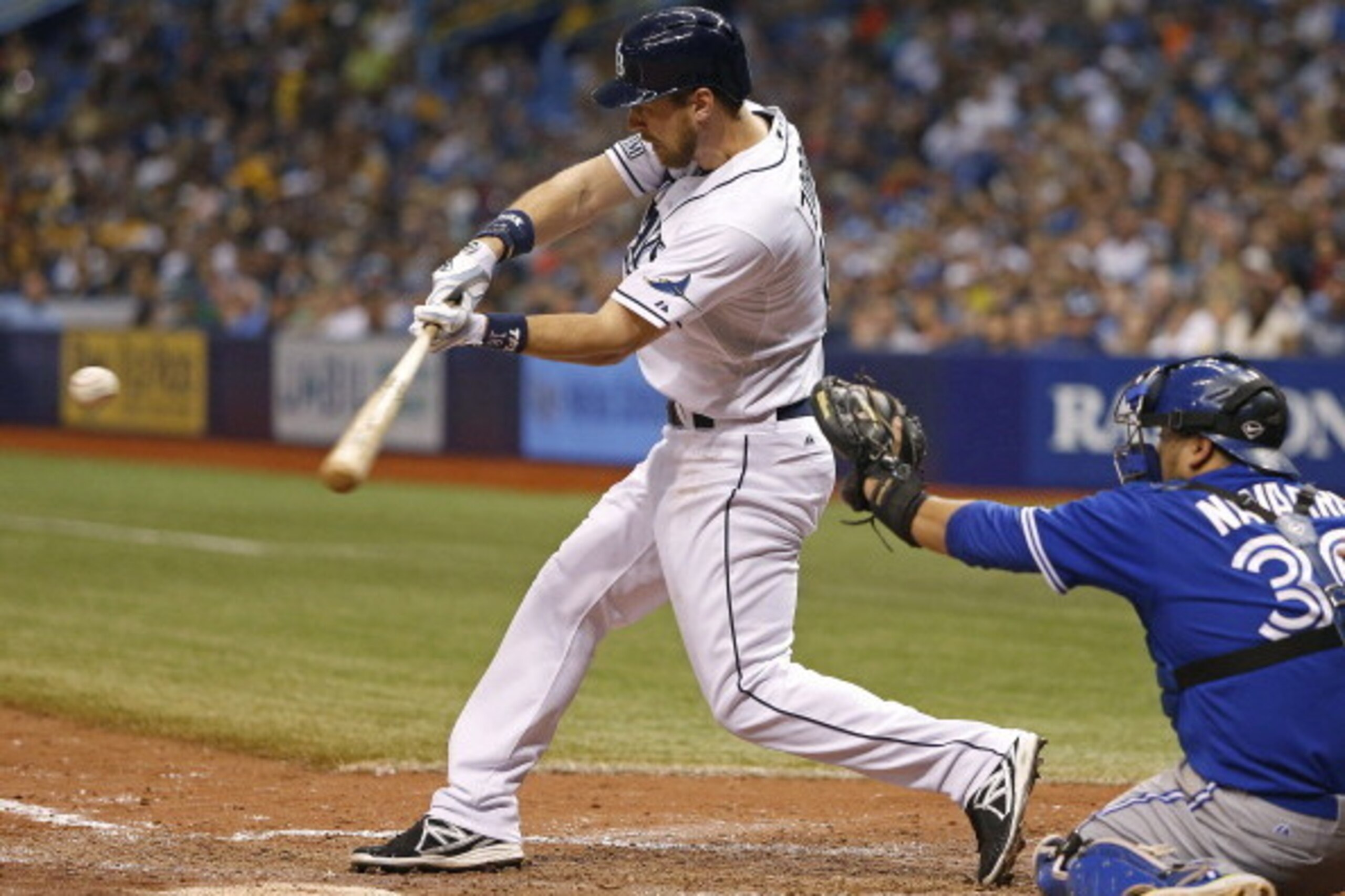 ST. PETERSBURG, FL - JULY 12:  Ben Zobrist #18 of the Tampa Bay Rays hits a sacrifice fly to center field in front of catcher Dioner Navarro #30 of the Toronto Blue Jays to score teammate Yunel Escobar during the seventh inning of a game on July 12, 2014 
