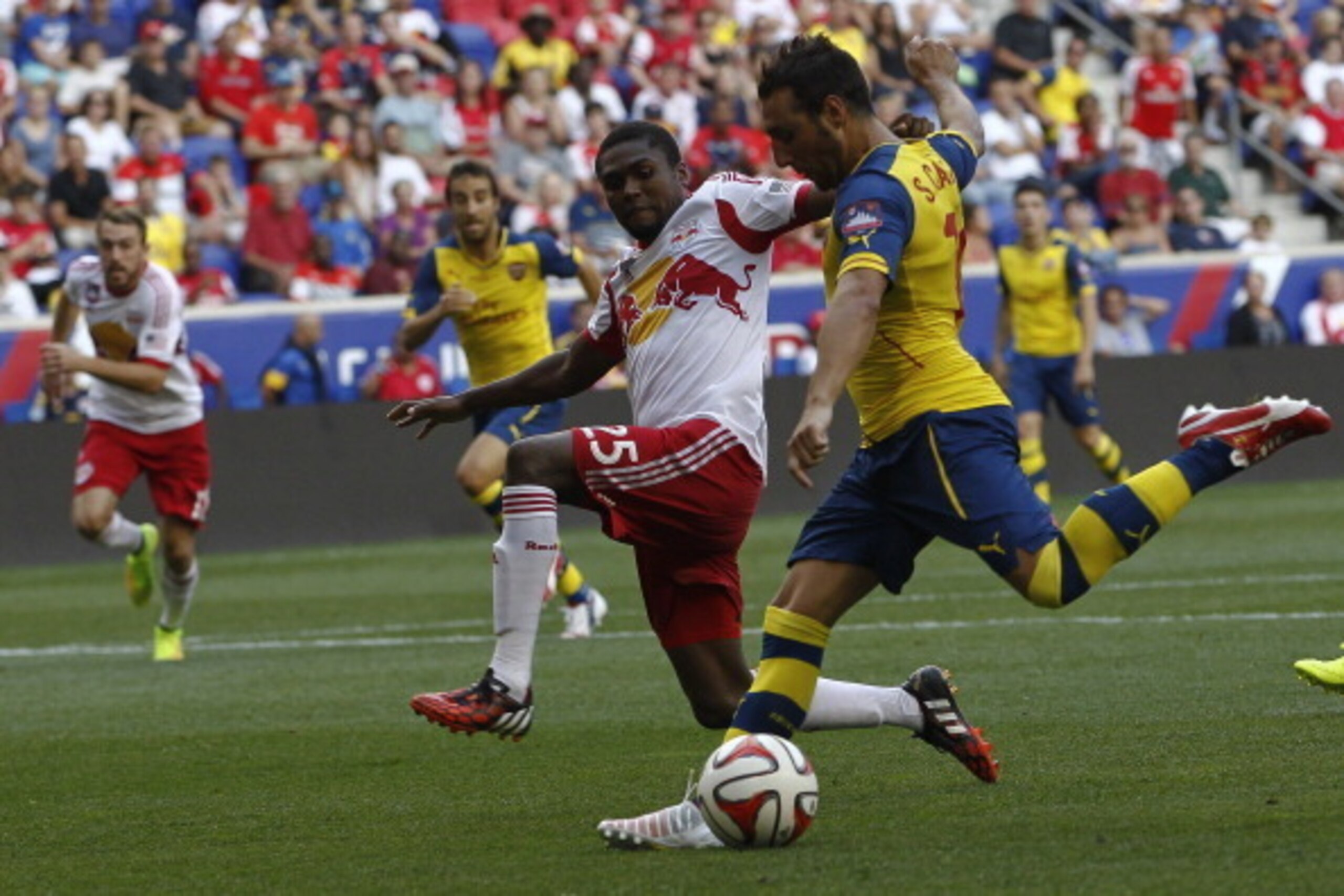 HARRISON, NJ - JULY 26: Santi Cazorla #19 of Arsenal fights for the ball with Chris Duvall #25 of New York Red Bulls during their friendly match at Red Bull Arena on July 26, 2014 in Harrison, NJ. (Photo by Jeff Zelevansky/Getty Images) HARRISON, NJ - JULY 26: Santi Cazorla #19 of Arsenal fights for the ball with Chris Duvall #25 of New York Red Bulls during their friendly match at Red Bull Arena on July 26, 2014 in Harrison, NJ. (Photo by Jeff Zelevansky/Getty Images)