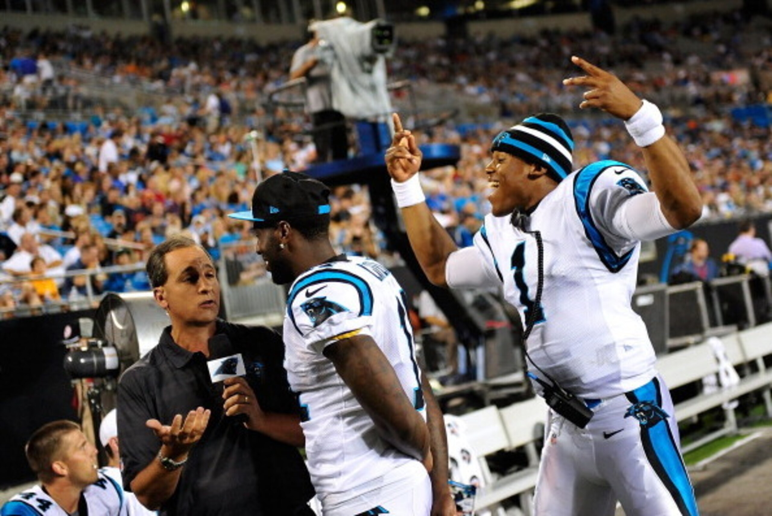 CHARLOTTE, NC - AUGUST 09:  Cam Newton #1 of the Carolina Panthers photobombs a television interview with teammate Brandon LaFell #11 during a preseason win over the Chicago Bears at Bank of America Stadium on August 9, 2013 in Charlotte, North Carolina. 
