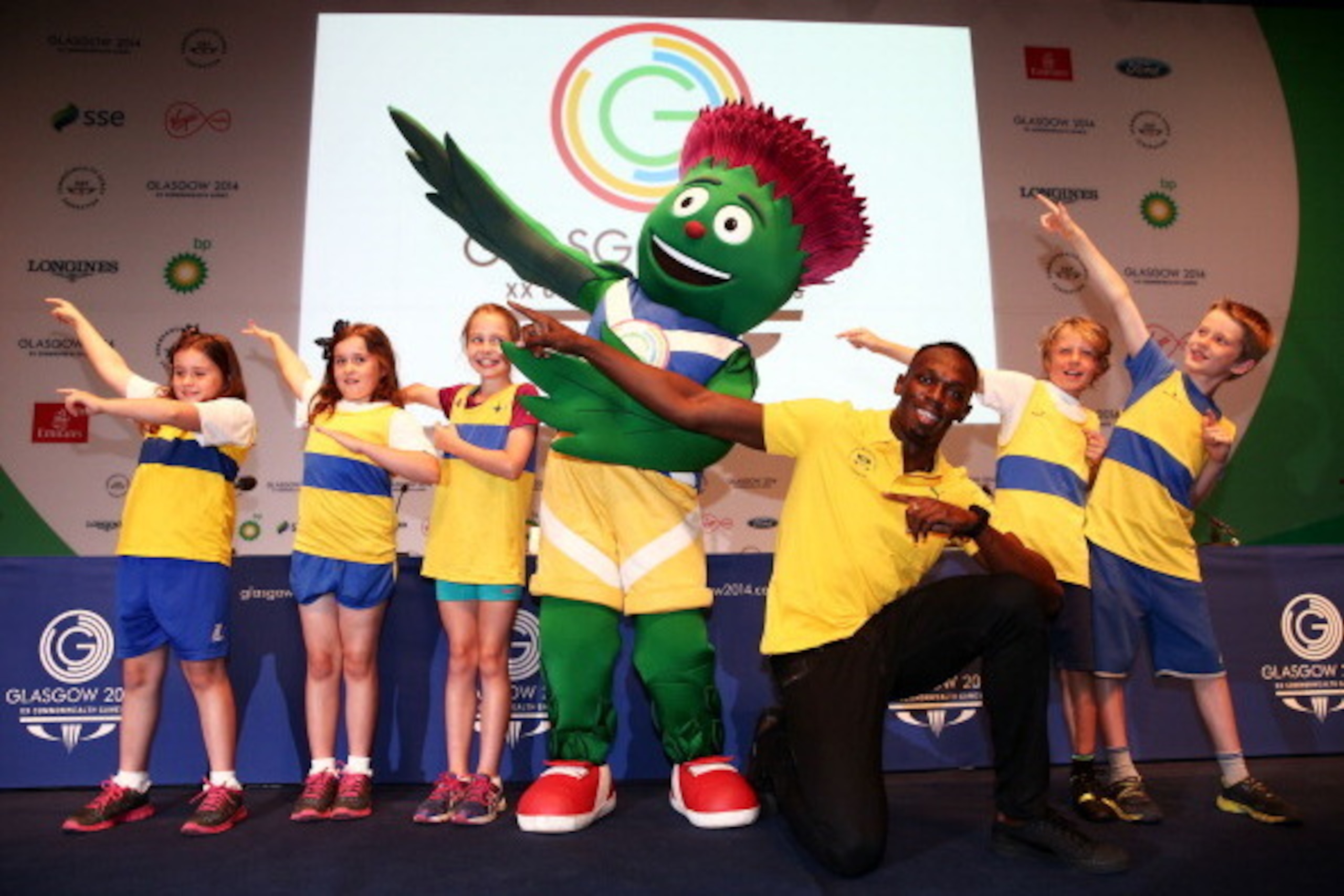GLASGOW, SCOTLAND - JULY 26:  Athlete Usain Bolt of Jamaica (3R) poses with Clyde the mascot and children from Giffnock North Amateur Athletics Club during a photocall at the Main Press Centre (MPC) during day three of the Glasgow 2014 Commonwealth Games 