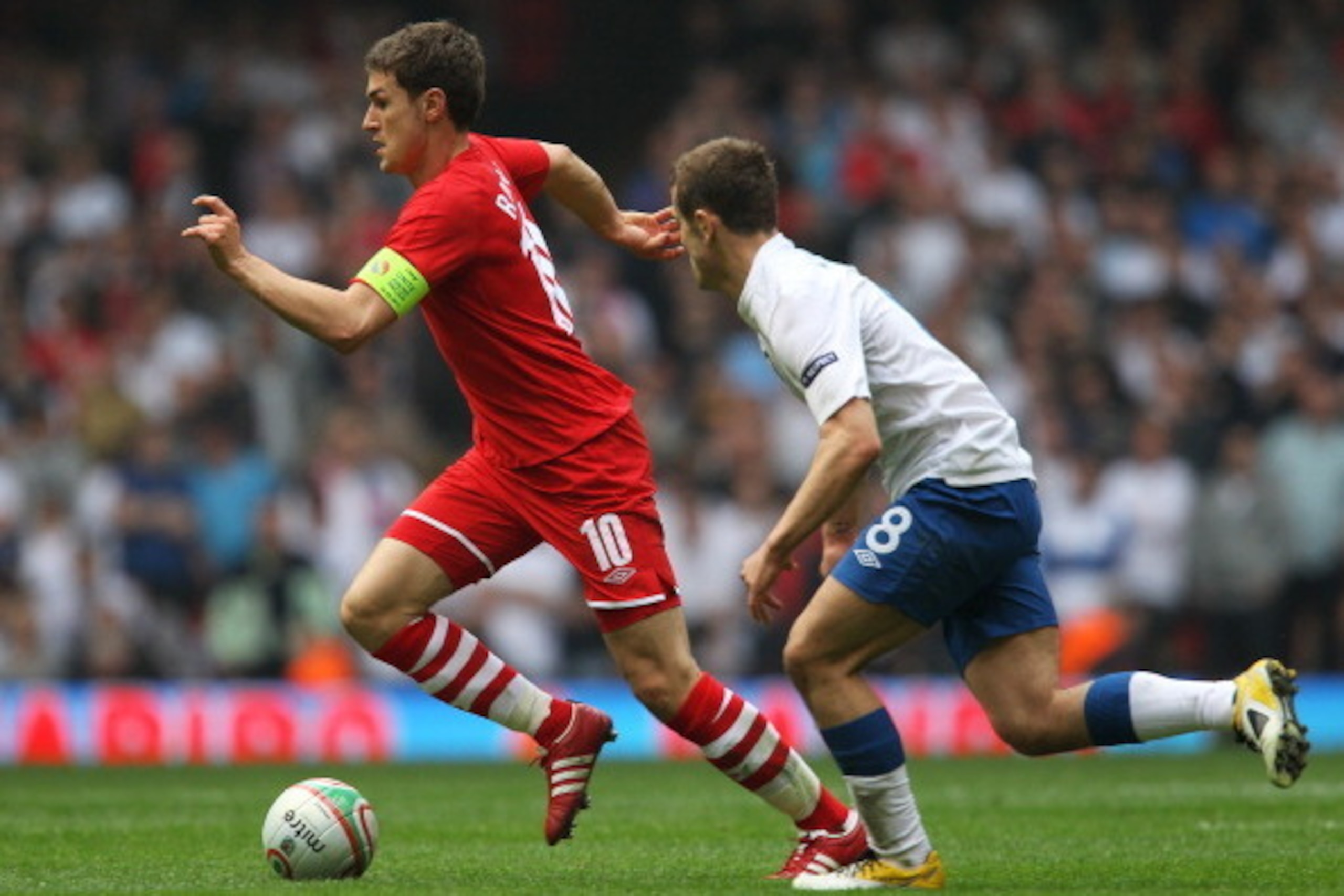 CARDIFF, WALES - MARCH 26: Aaron Ramsey of Wales takes the ball past Jack Wilshere of England during the UEFA EURO 2012 Group G qualifying match between Wales and England at the Millennium Stadium on March 26, 2011 in Cardiff, Wales.  (Photo by Alex Lives