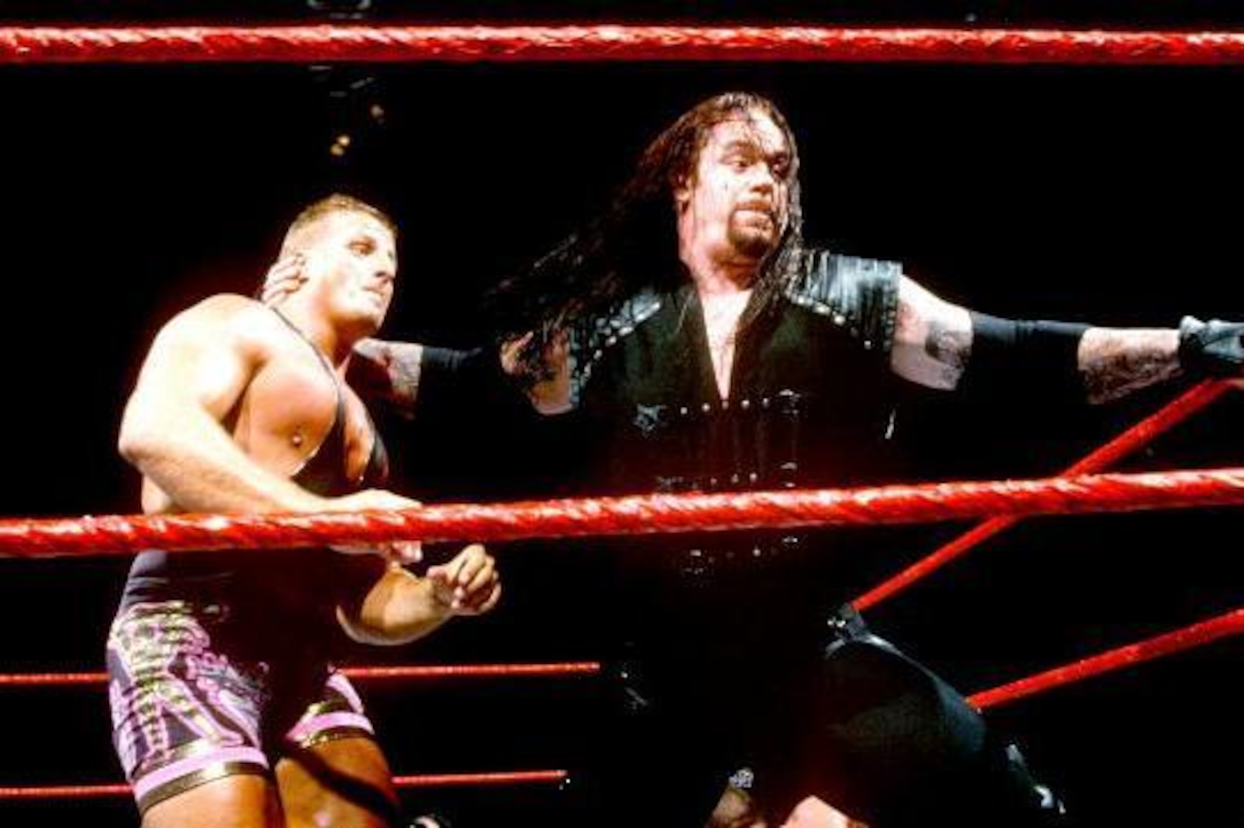 Undertaker looks to send Owen Hart's head into the turnbuckle.