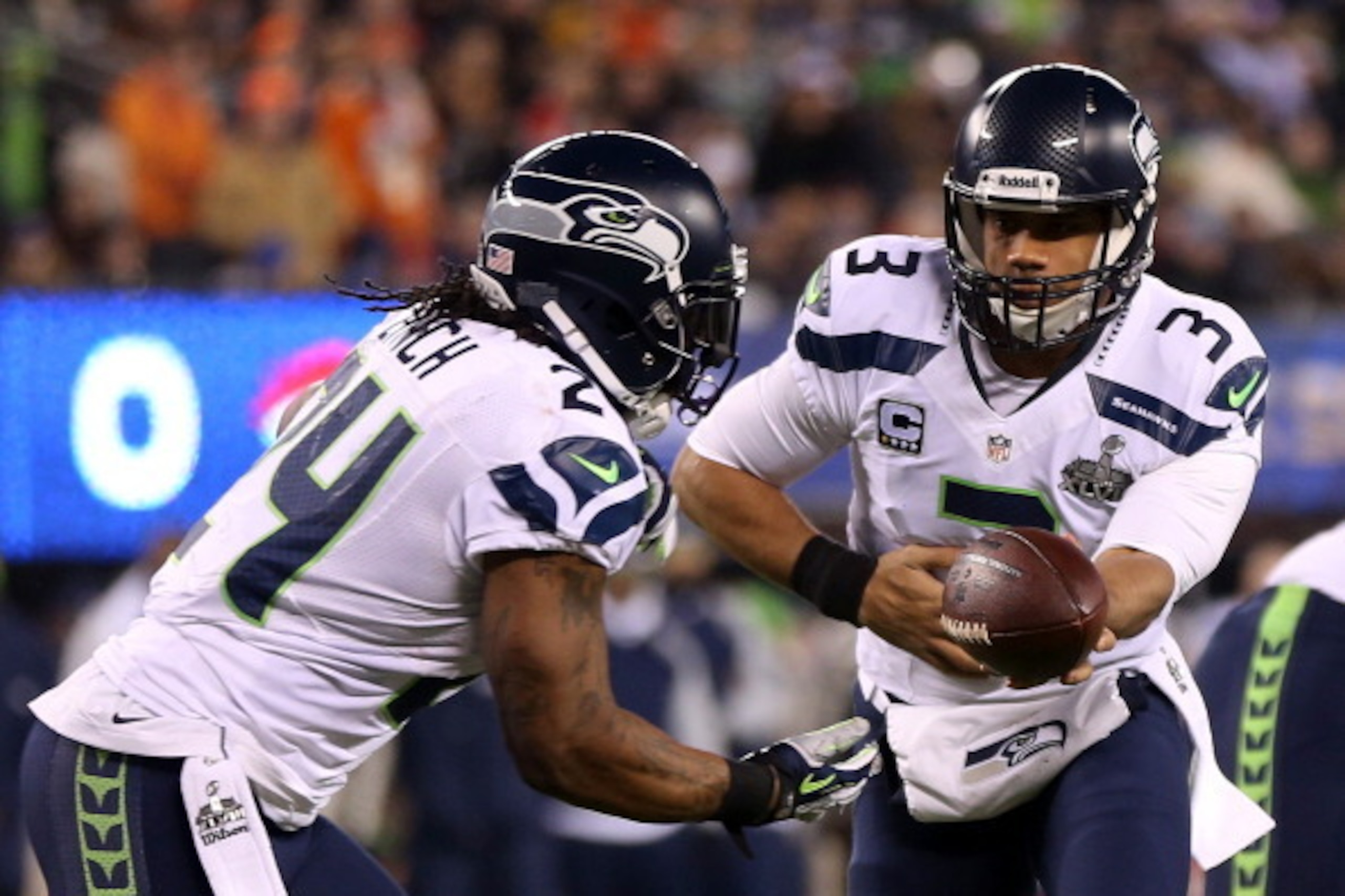 EAST RUTHERFORD, NJ - FEBRUARY 02:  Quarterback Russell Wilson #3 looks ot hand off to running back Marshawn Lynch #24 of the Seattle Seahawks during Super Bowl XLVIII against the Denver Broncos at MetLife Stadium on February 2, 2014 in East Rutherford, N