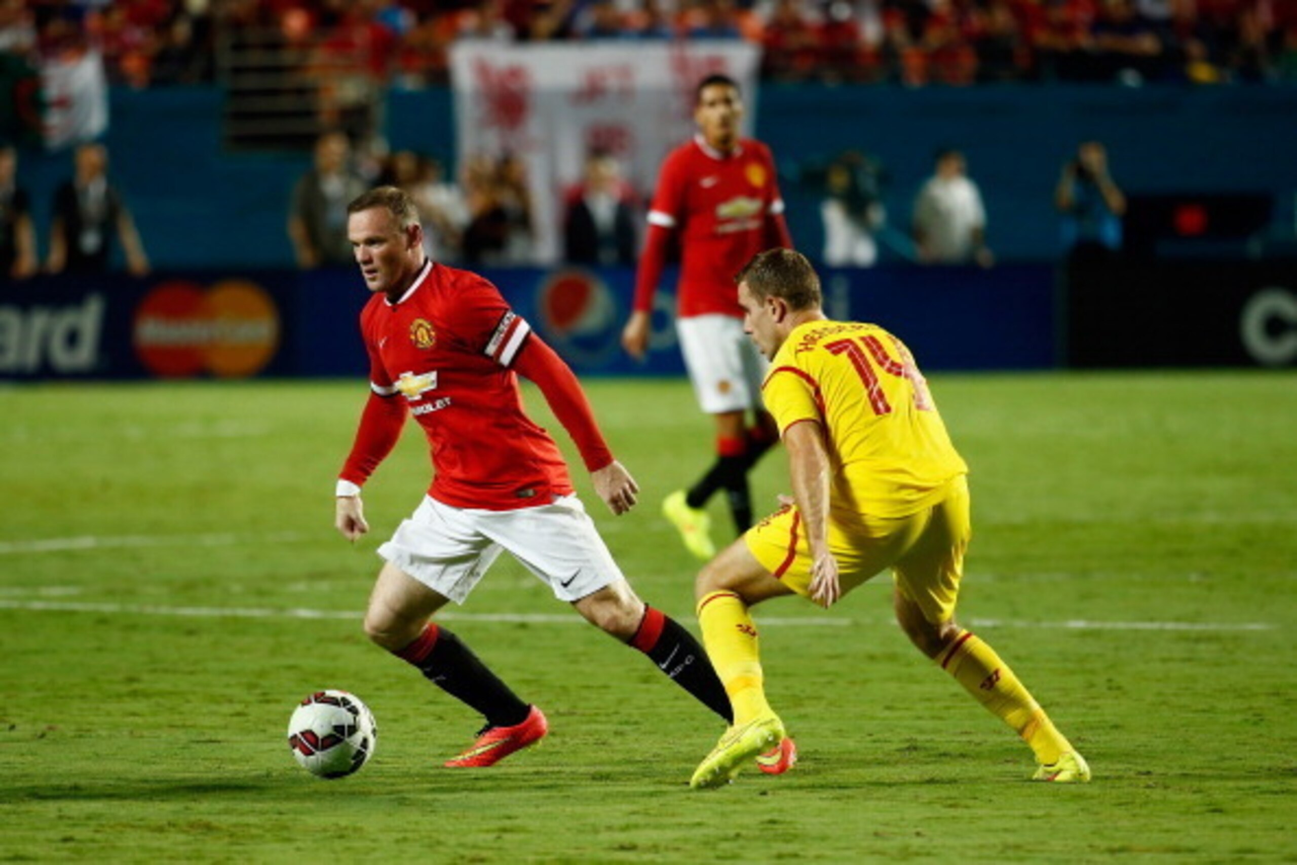 MIAMI GARDENS, FL - AUGUST 04: Wayne Rooney #10 of Manchester United is challenged by Jordan Henderson #14 of Liverpool in the Guinness International Champions Cup 2014 Final at Sun Life Stadium on August 4, 2014 in Miami Gardens, Florida.  (Photo by Chri