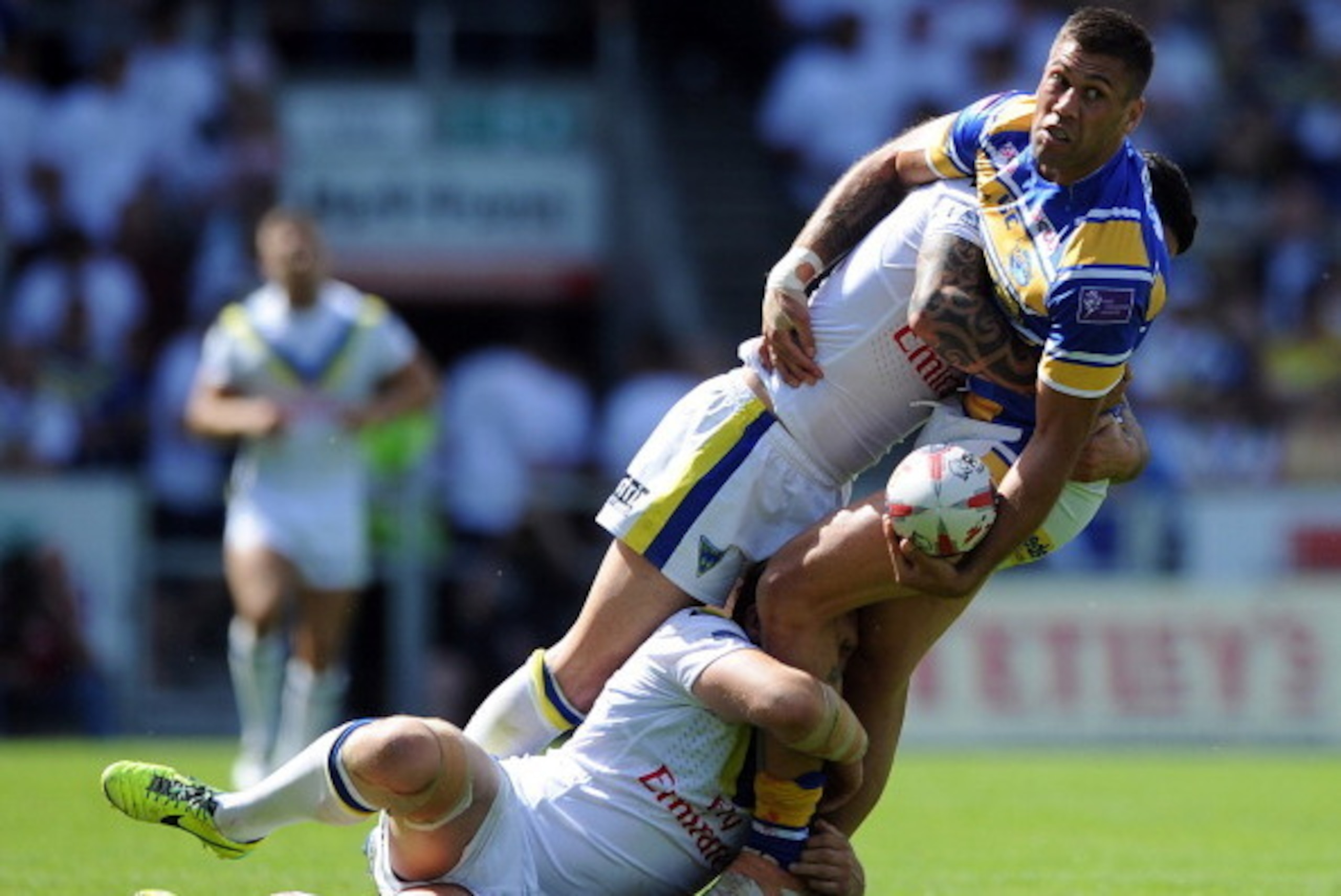 ST HELENS, ENGLAND - AUGUST 09: Joel Moon of Leeds Rhinos is tackled by Ashley Westwood and Chris Bridge of Warrington Wolves during the Tetley's Challenge Cup Semi Final match between Leeds Rhinos and Warrington Wolves at Langtree Park on August 09, 2014