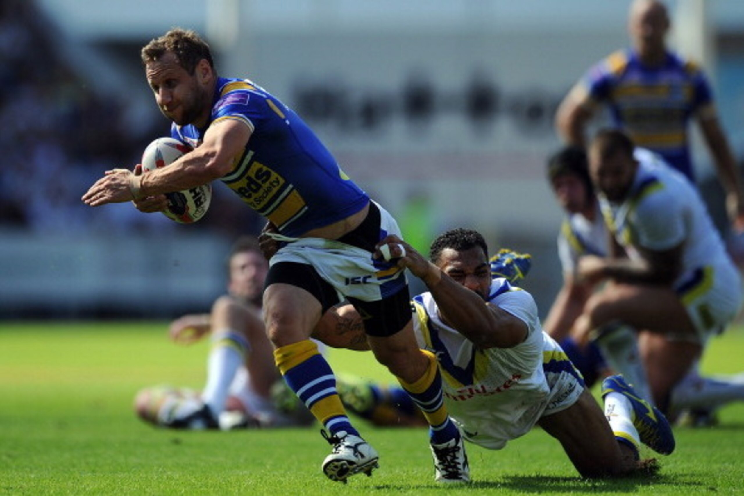 ST HELENS, ENGLAND - AUGUST 09: Rob Burrow of Leeds Rhinos is tackled by Ryan Atkins of Warrington Wolves during the Tetley's Challenge Cup Semi Final match between Leeds Rhinos and Warrington Wolves at Langtree Park on August 09, 2014 in St Helens, Engla