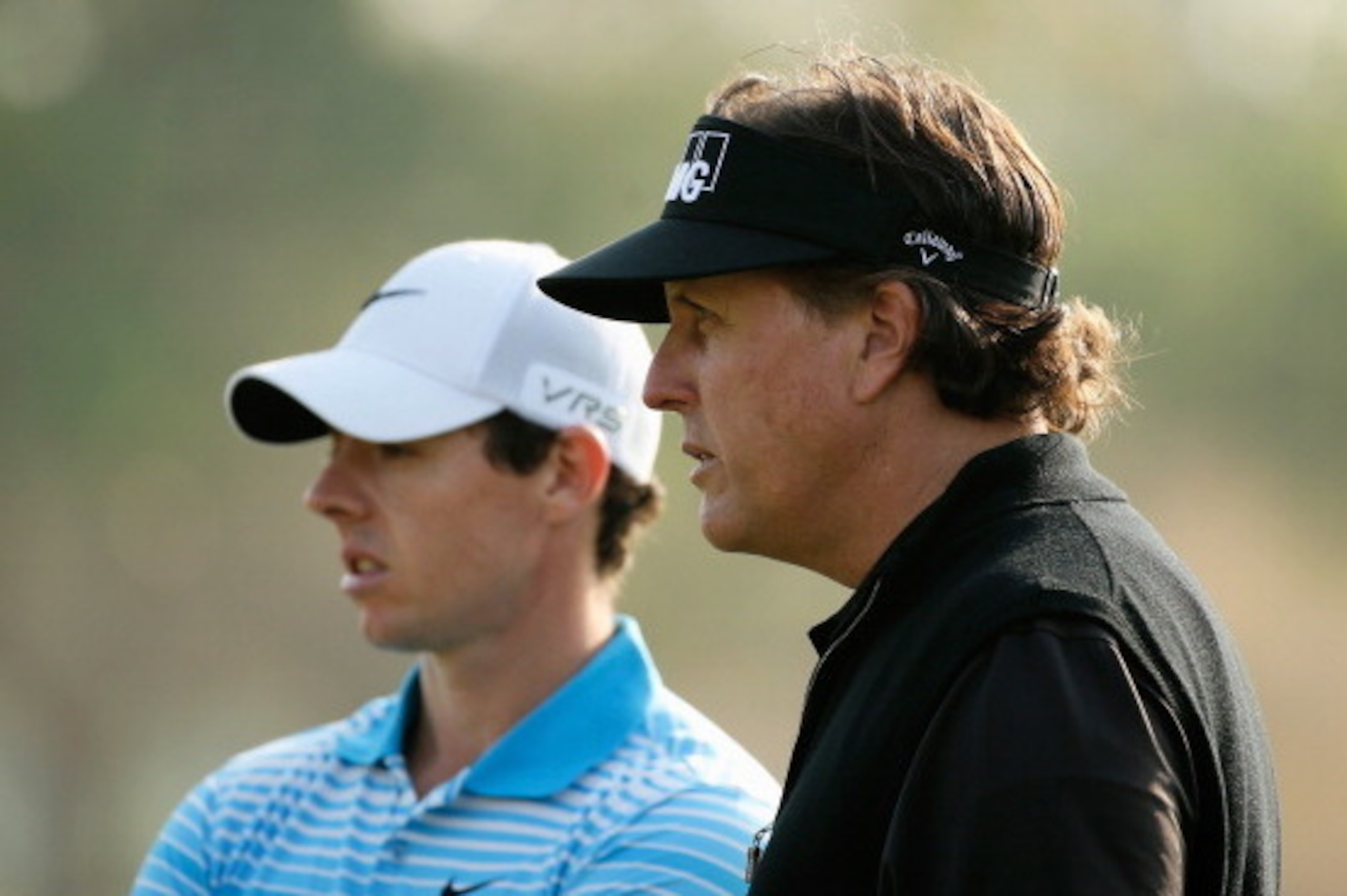 ABU DHABI, UNITED ARAB EMIRATES - JANUARY 16:  Rory McIlroy of Northern Ireland (L) waits on the 16th green with Phil Mickelson of the USA during the first round of the Abu Dhabi HSBC Golf Championship at the Abu Dhabi Golf Clubon January 16, 2014 in Abu 