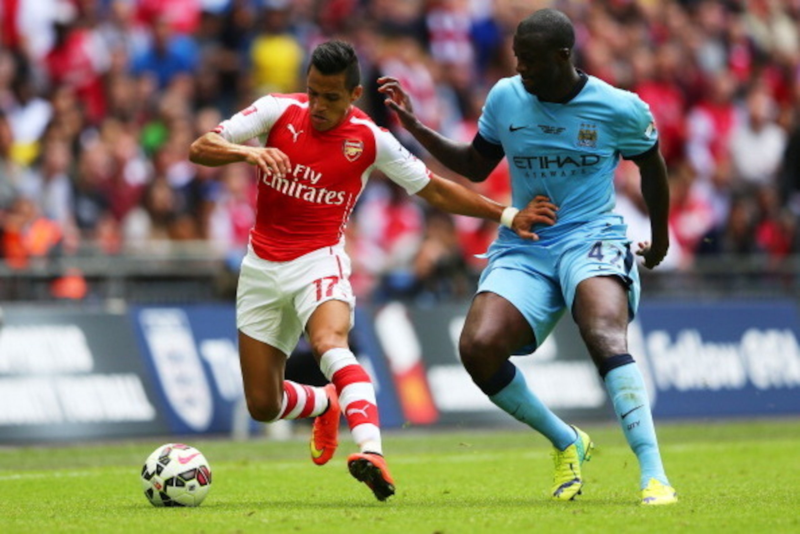 LONDON, ENGLAND - AUGUST 10: Alexis Sanchez of Arsenal competes with Yaya Toure of Manchester City during the FA Community Shield match between Manchester City and Arsenal at Wembley Stadium on August 10, 2014 in London, England. (Photo by Clive Mason/Ge LONDON, ENGLAND - AUGUST 10: Alexis Sanchez of Arsenal competes with Yaya Toure of Manchester City during the FA Community Shield match between Manchester City and Arsenal at Wembley Stadium on August 10, 2014 in London, England. (Photo by Clive Mason/Ge