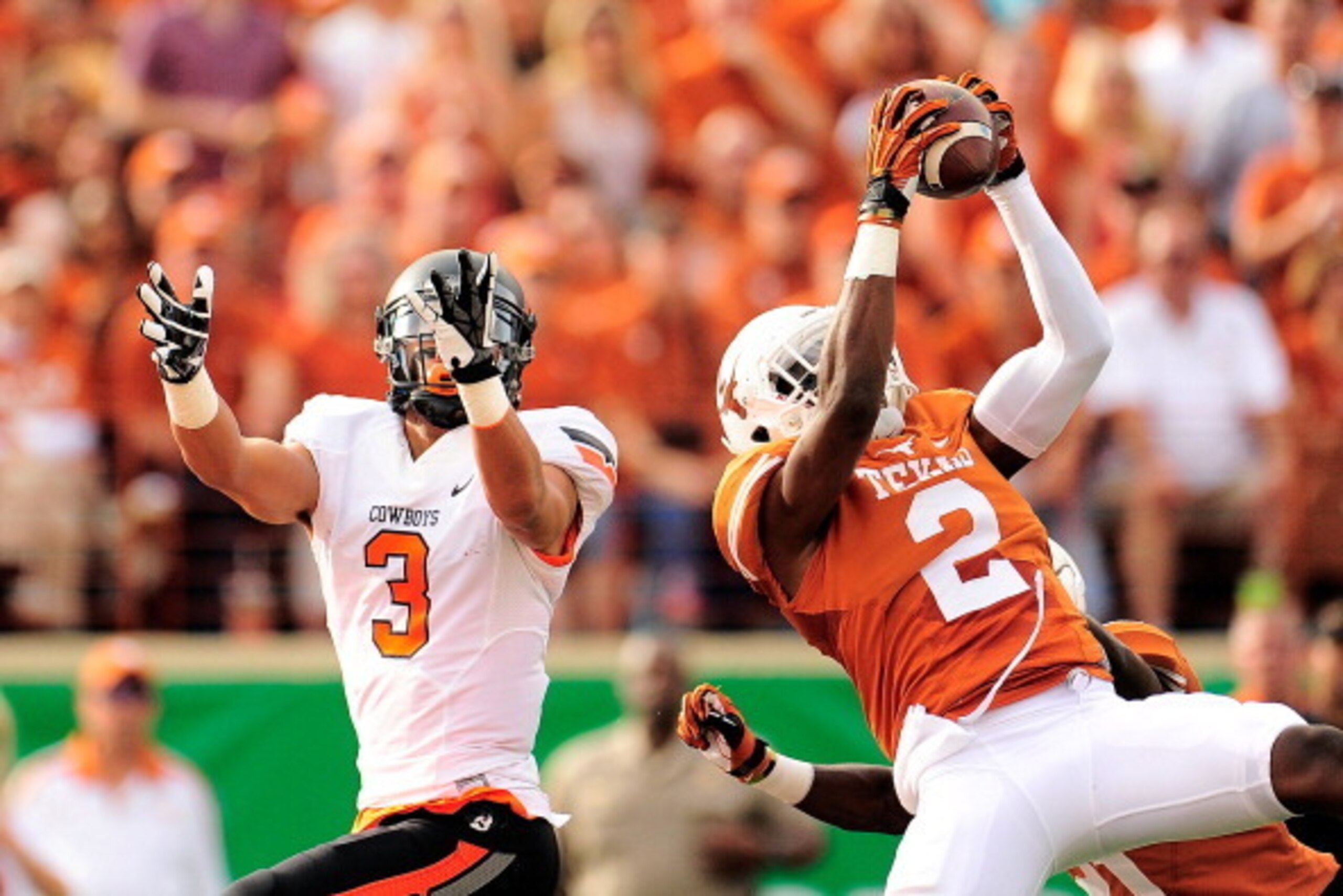 AUSTIN, TX - NOVEMBER 16:  Mykkele Thompson #2 of the Texas Longhorns intercepts a pass intended for Marcell Ateman #3 of the Oklahoma State Cowboys during a game at Darrell K Royal-Texas Memorial Stadium on November 16, 2013 in Austin, Texas.  (Photo by 