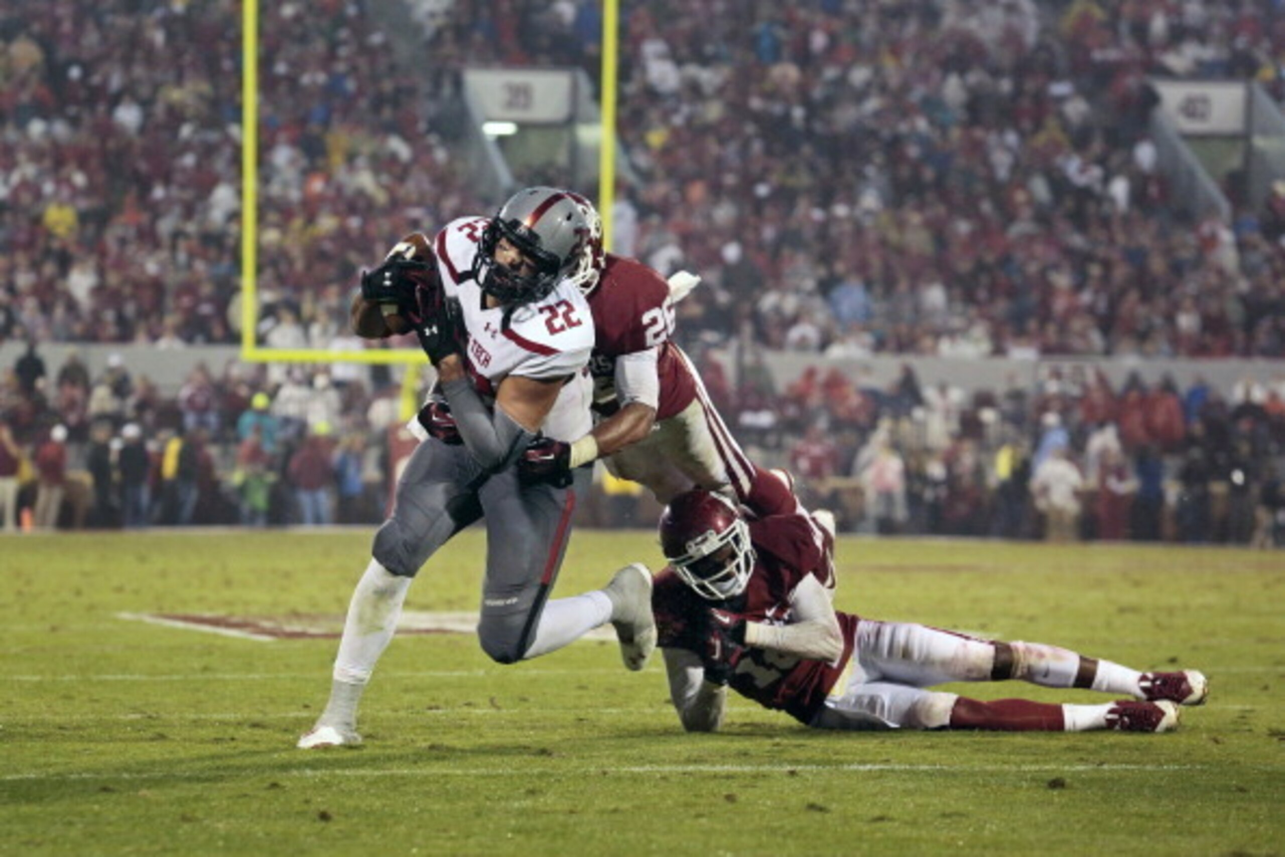 NORMAN, OK - OCTOBER 26:  Linebacker Jordan Evans #26 and defensive back Quentin Hayes #10 of the Oklahoma Sooners try to take down tight end Jace Amaro #22 of the Texas Tech Red Raiders October 26, 2013 at Gaylord Family-Oklahoma Memorial Stadium in Norm