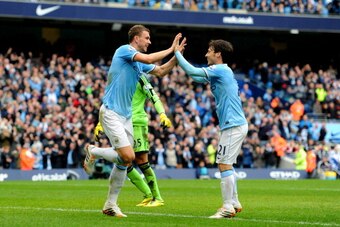 MANCHESTER, ENGLAND - APRIL 05:  Edin Dzeko of Manchester City is congratulated by teammate David Silva (R) after scoring his team's third goal past goalkeeper Paulo Gazzaniga of Southampton during the Barclays Premier League match between Manchester City