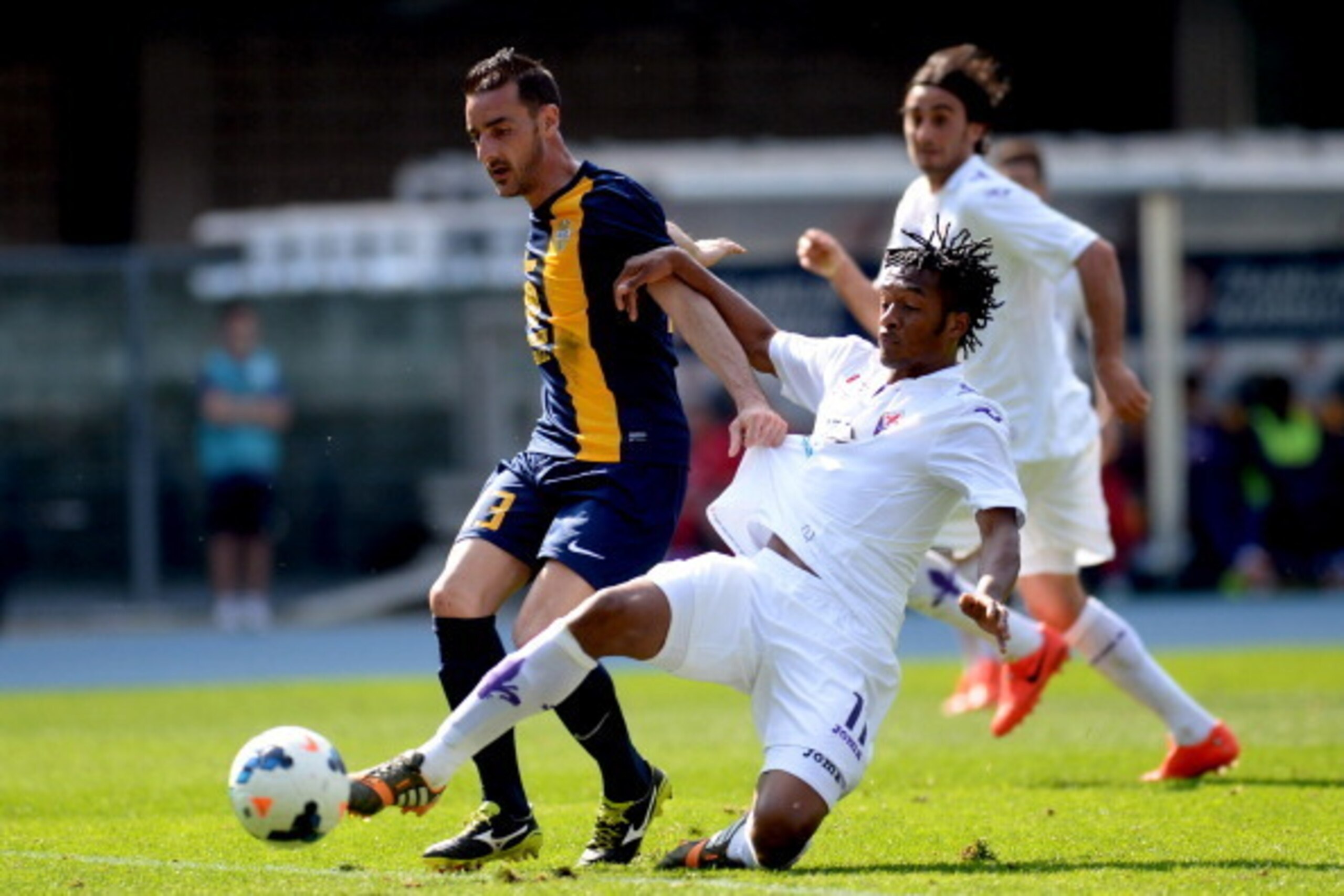 VERONA, ITALY - APRIL 13:  Michelangelo Albertazzi (L) of Hellas Verona battles for the ball with  Juan Cuadrado of ACF Fiorentina during the Serie A match between Hellas Verona FC and ACF Fiorentina at Stadio Marc'Antonio Bentegodi on April 13, 2014 in V
