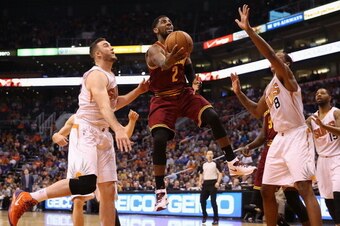 PHOENIX, AZ - MARCH 12:  Kyrie Irving #2 of the Cleveland Cavaliers lays up a shot against Channing Frye #8 of the Phoenix Suns during the first half of the NBA game at US Airways Center on March 12, 2014 in Phoenix, Arizona.  NOTE TO USER: User expressly