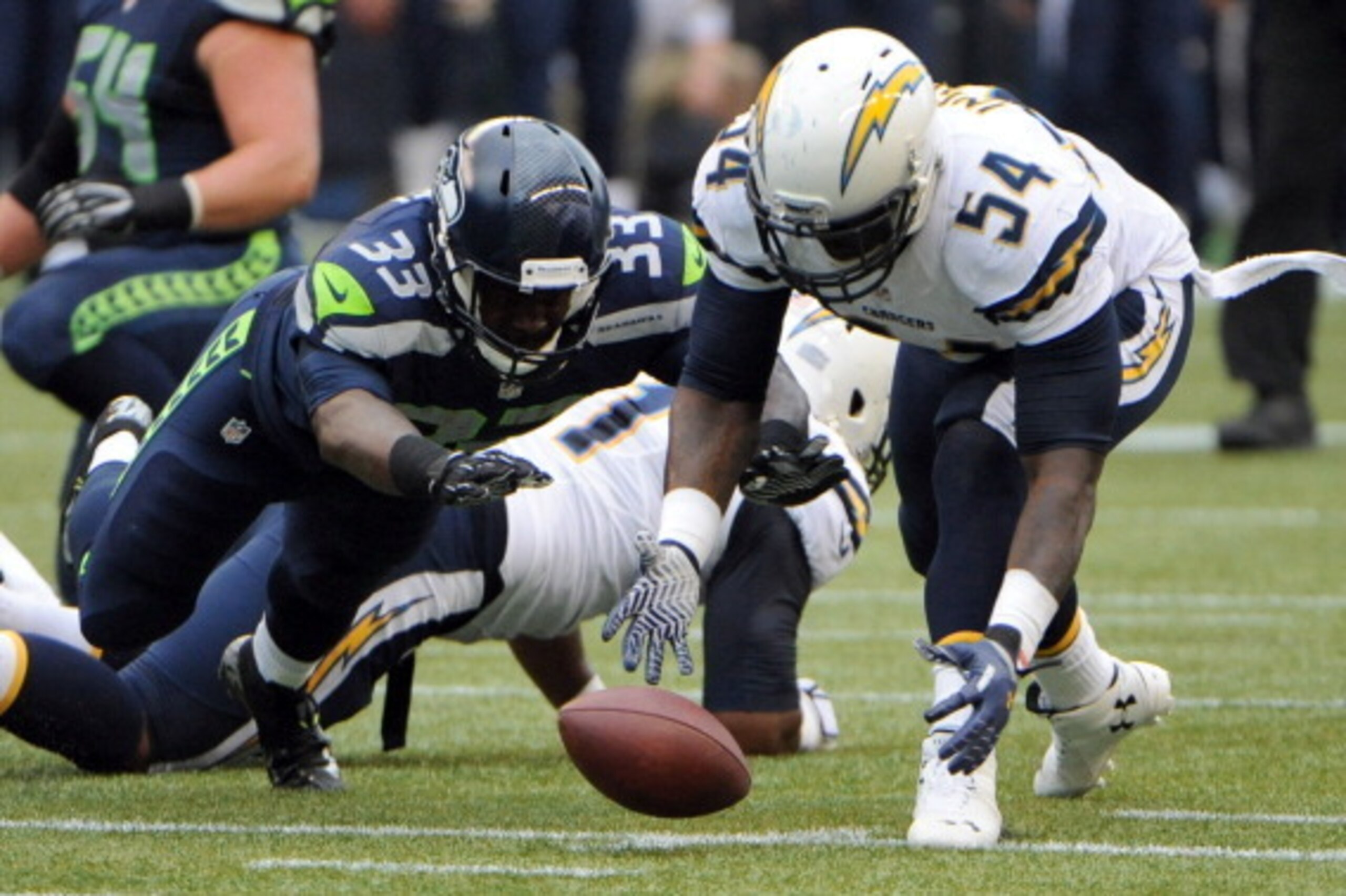 SEATTLE, WA - AUGUST 15: Running back Christine Michael #33 of the Seattle Seahawks recovers a fumble as outside linebacker Melvin Ingram #54 of the San Diego Chargers closes in during the first quarter of the game at CenturyLink Field on August 15, 2014 