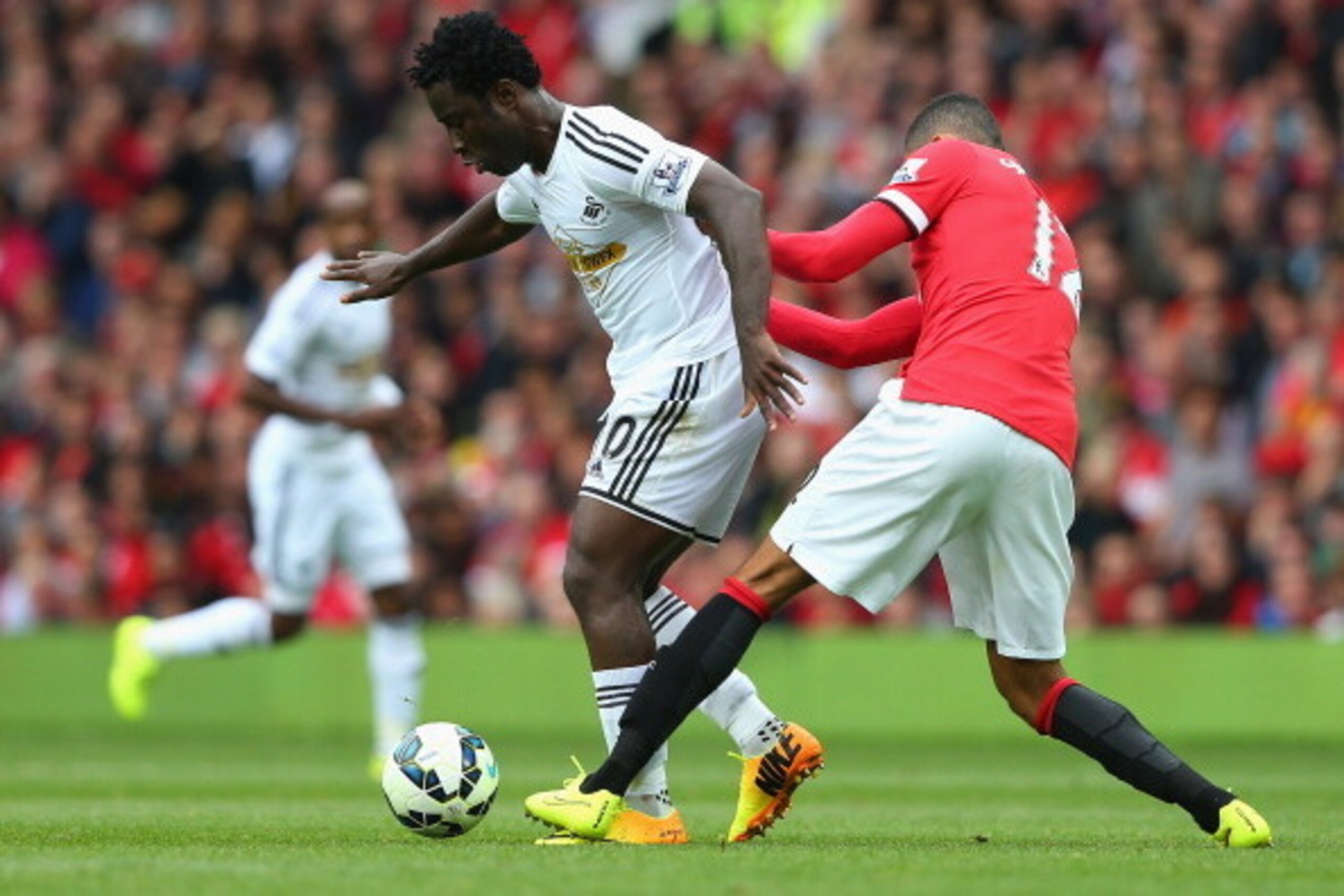 MANCHESTER, ENGLAND - AUGUST 16:  Wilfried Bony of Swansea City is challenged by Chris Smalling of Manchester United during the Barclays Premier League match between Manchester United and Swansea City at Old Trafford on August 16, 2014 in Manchester, Engl