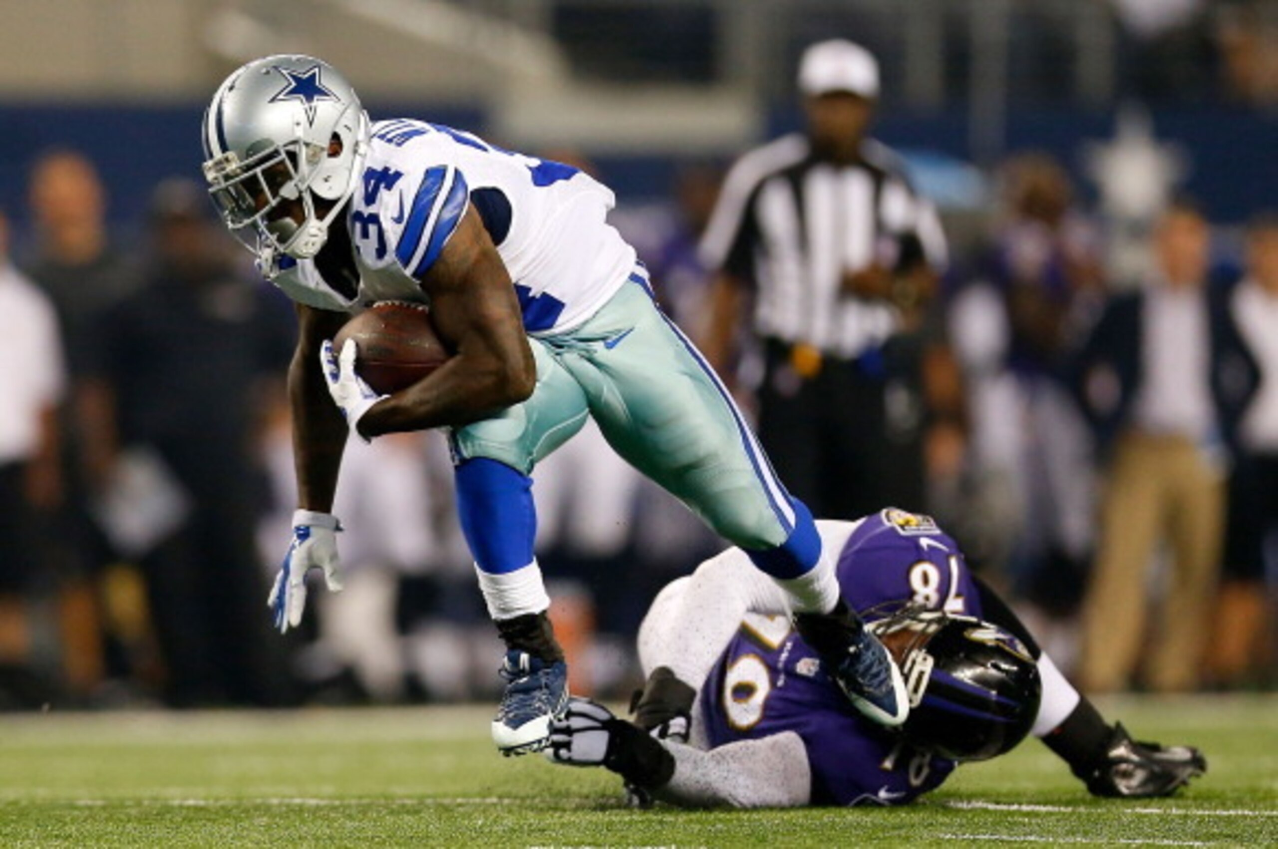 ARLINGTON, TX - AUGUST 16:  Ryan Williams #34 of the Dallas Cowboys breaks the tackle attempt by Derrick Hopkins #78 of the Baltimore Ravens in the second half  of their preseason game at AT&T Stadium on August 16, 2014 in Arlington, Texas.  (Photo by Tom