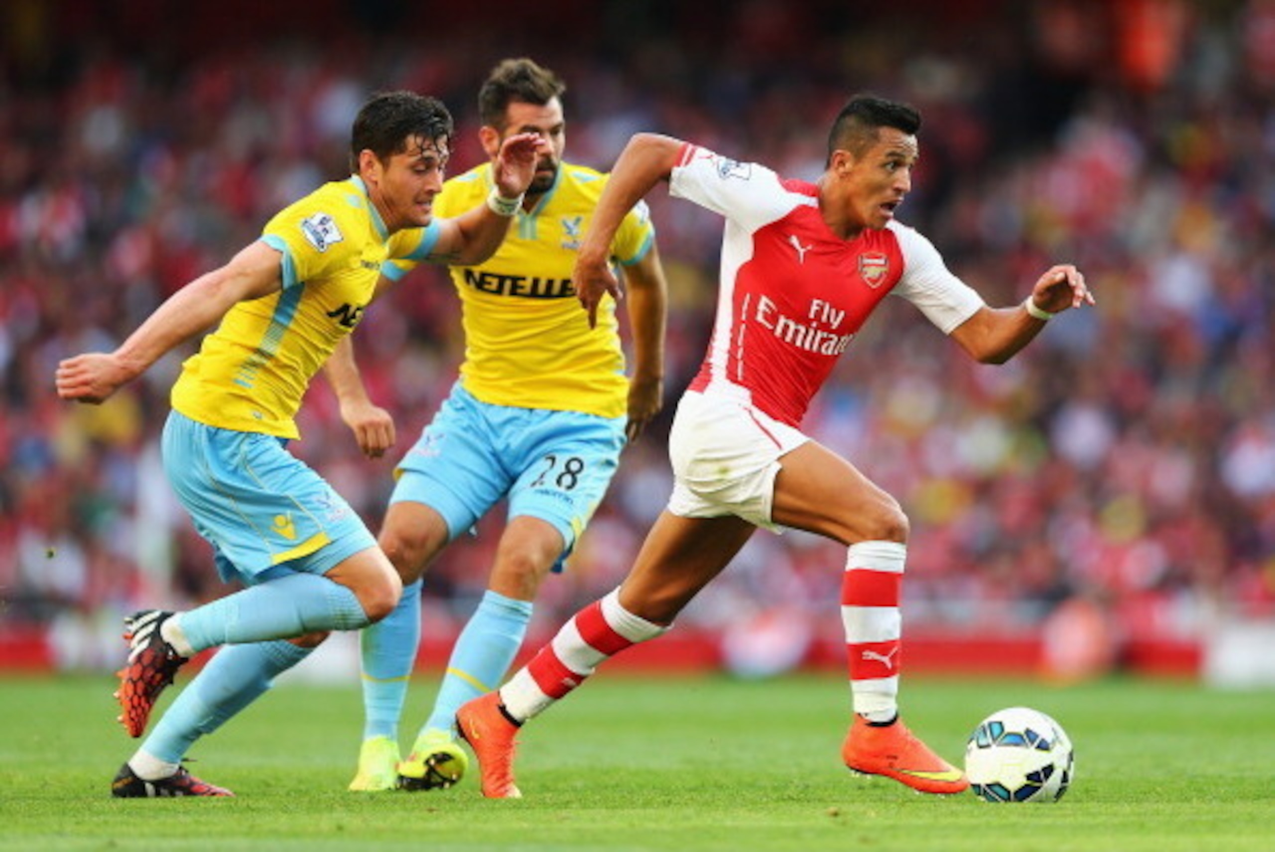 LONDON, ENGLAND - AUGUST 16:  Alexis Sanchez of Arsenal goes past Joel Ward (L) and Joe Ledley of Crystal Palace during the Barclays Premier League match between Arsenal and Crystal Palace at Emirates Stadium on August 16, 2014 in London, England.  (Photo