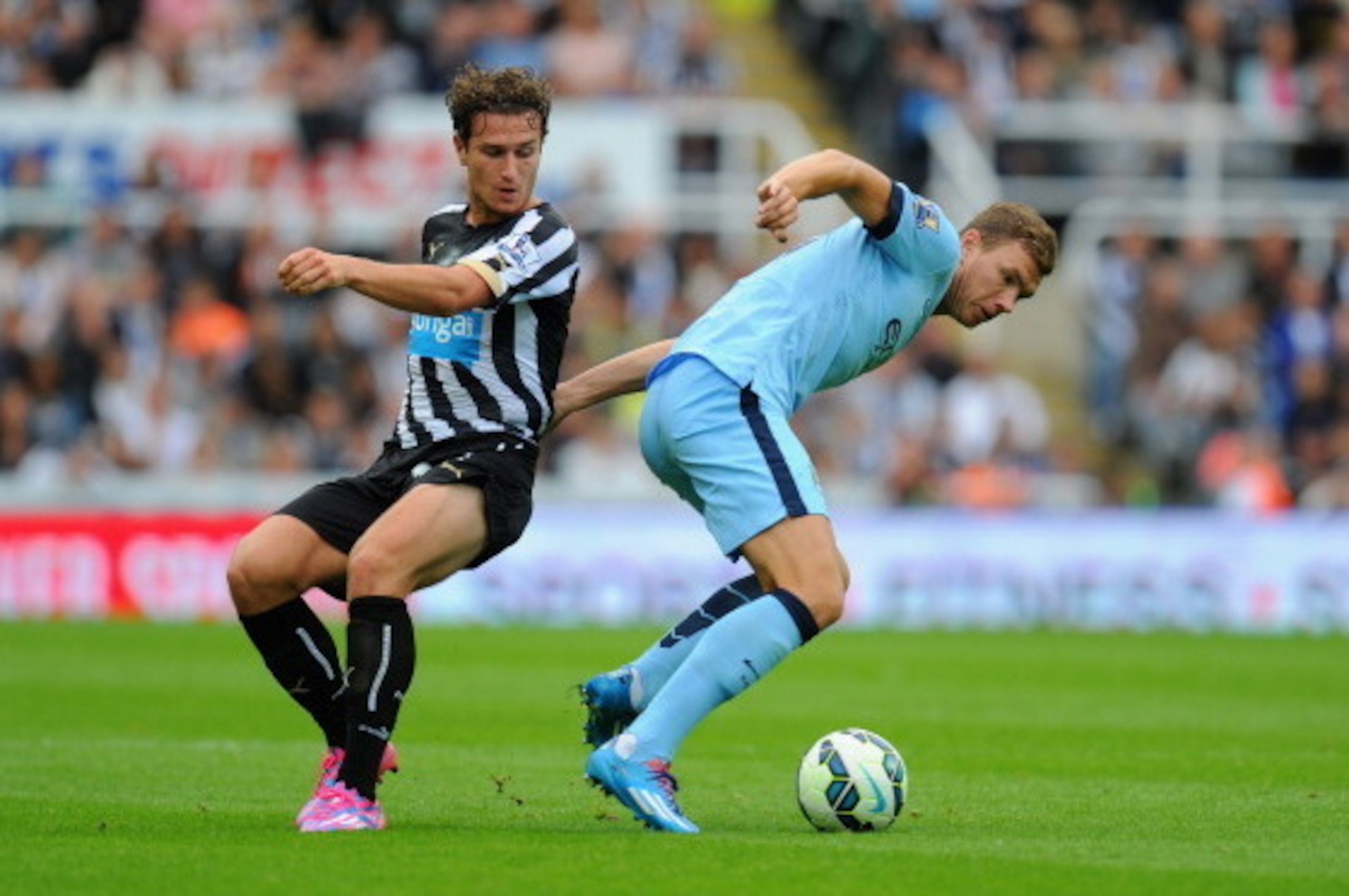 NEWCASTLE UPON TYNE, ENGLAND - AUGUST 17:  Edin Dzeko of Man City (r) is challenged by Daryl Janmaat during the Barclays Premier League match between Newcastle United and Manchester City at St James' Park on August 17, 2014 in Newcastle upon Tyne, England