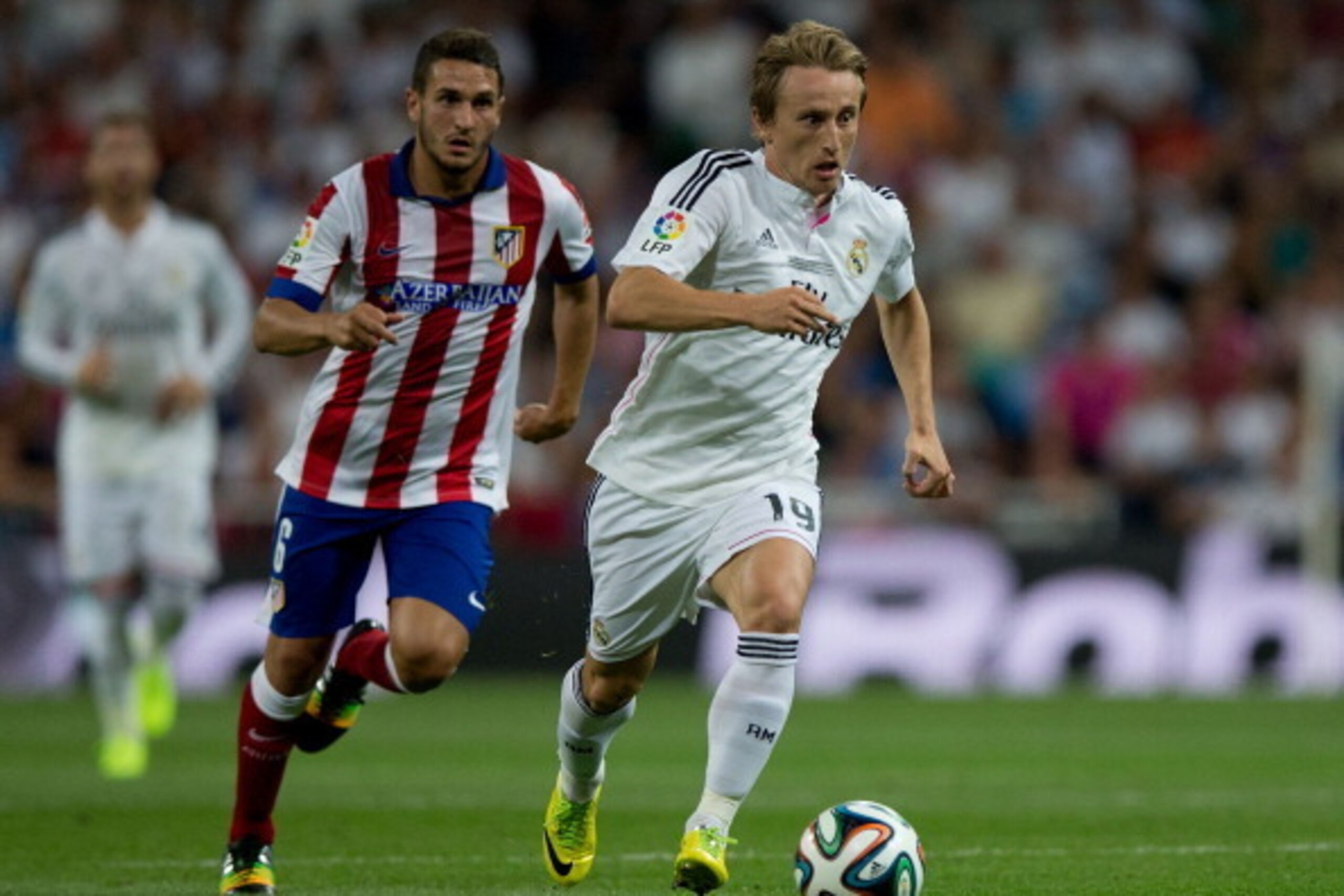 MADRID, SPAIN - AUGUST 19: Luka Modric (R) of Real Madrid CF competes for the ball ahead Koke of Atletico de Madrid (L) during the Supercopa first leg match between Real Madrid and Club Atletico de Madrid at Estadio Santiago Bernabeu on August 19, 2014 in
