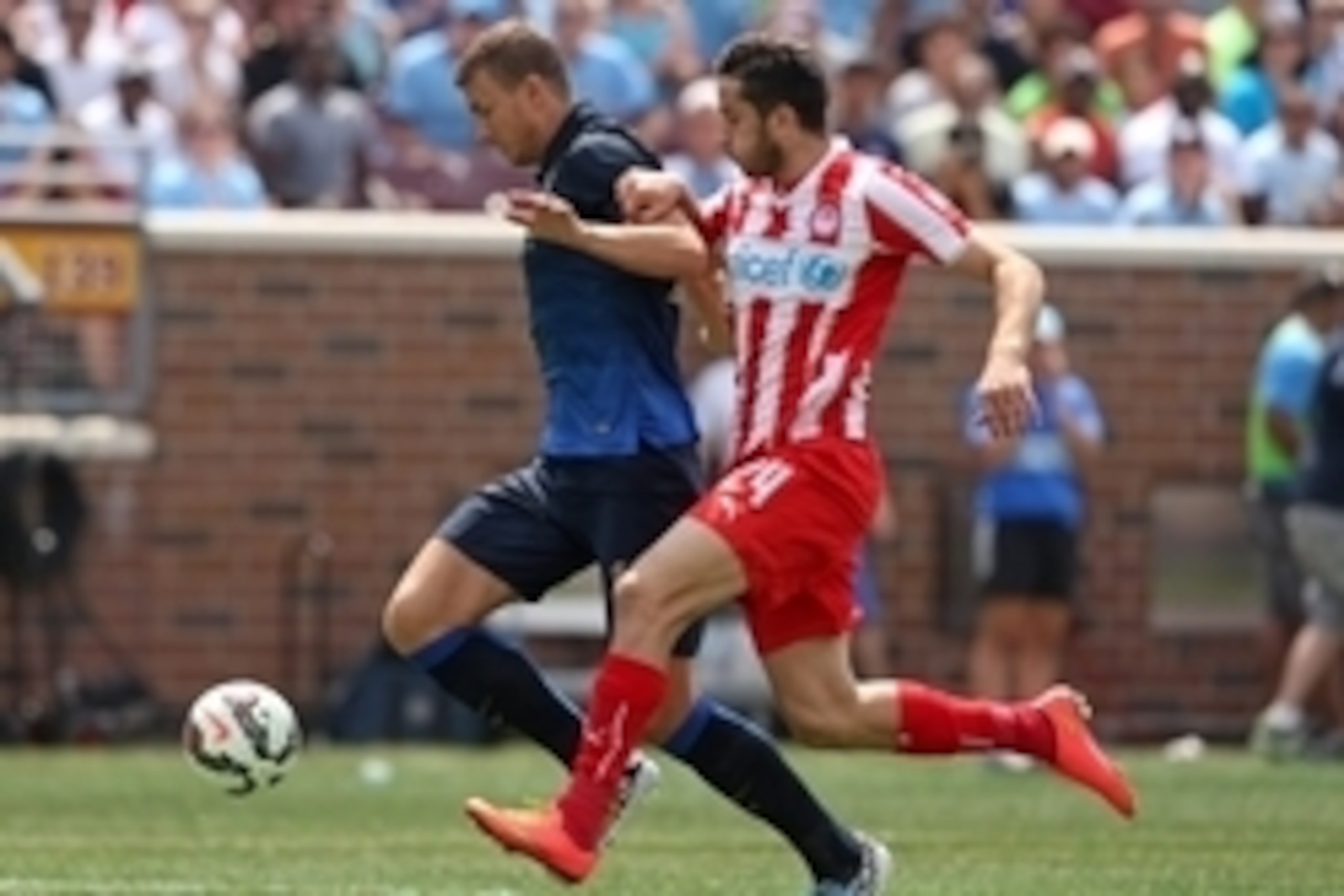 Aug 2, 2014; Minneapolis, MN, USA; Manchester City forward forward Edin Dzeko (10) dribbles the ball past Olympiakos defender Kostas Manolas (24) during the first half at TCF Bank Stadium. Mandatory Credit: Brace Hemmelgarn-USA TODAY Sports