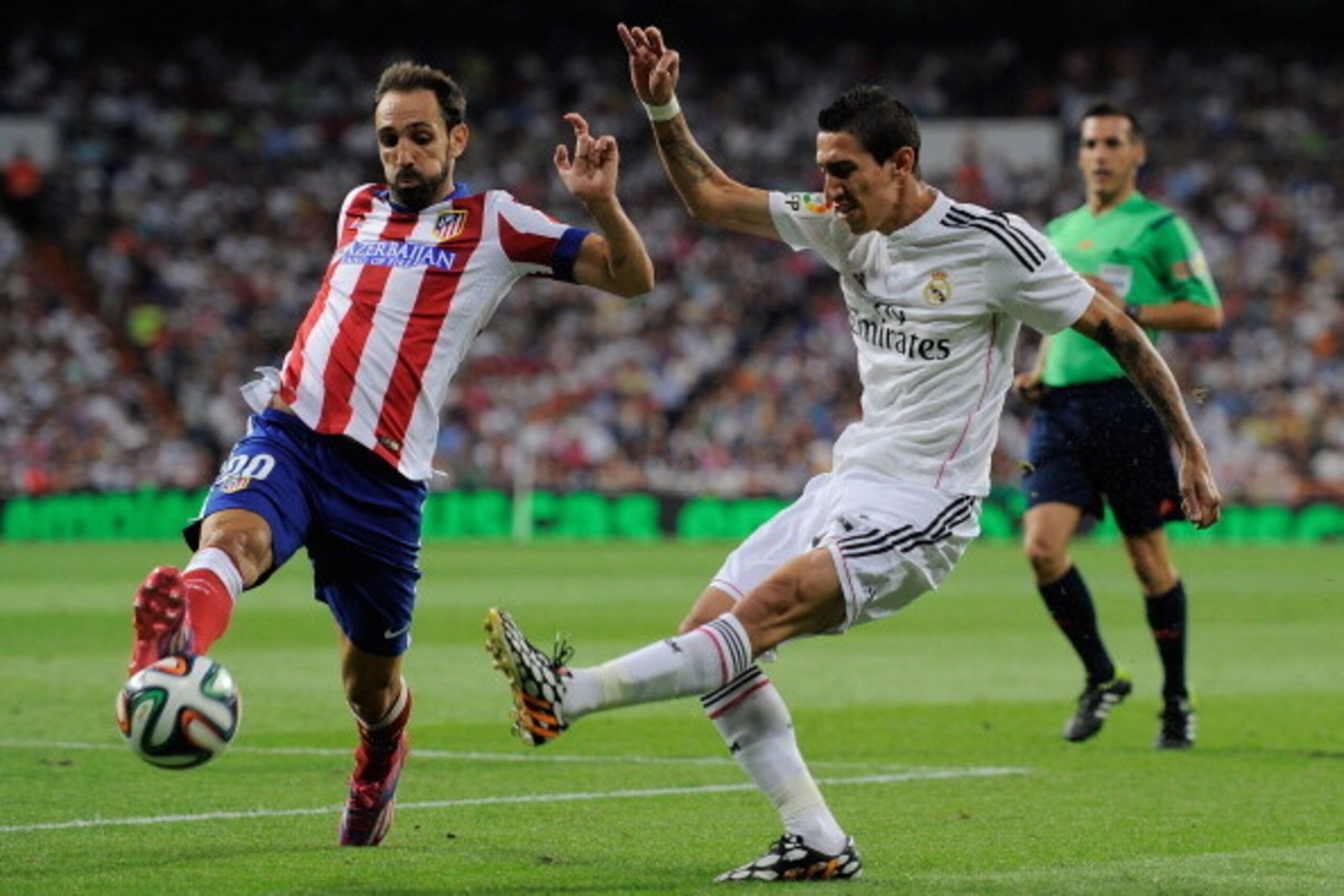 MADRID, SPAIN - AUGUST 19:  Angel di Maria (R) of Real Madrid shoots past Raul Garcia of Club Atletico de Madrid during the Supercopa first leg match between Real Madrid and Club Atletico de Madrid at Estadio Santiago Bernabeu on August 19, 2014 in Madrid